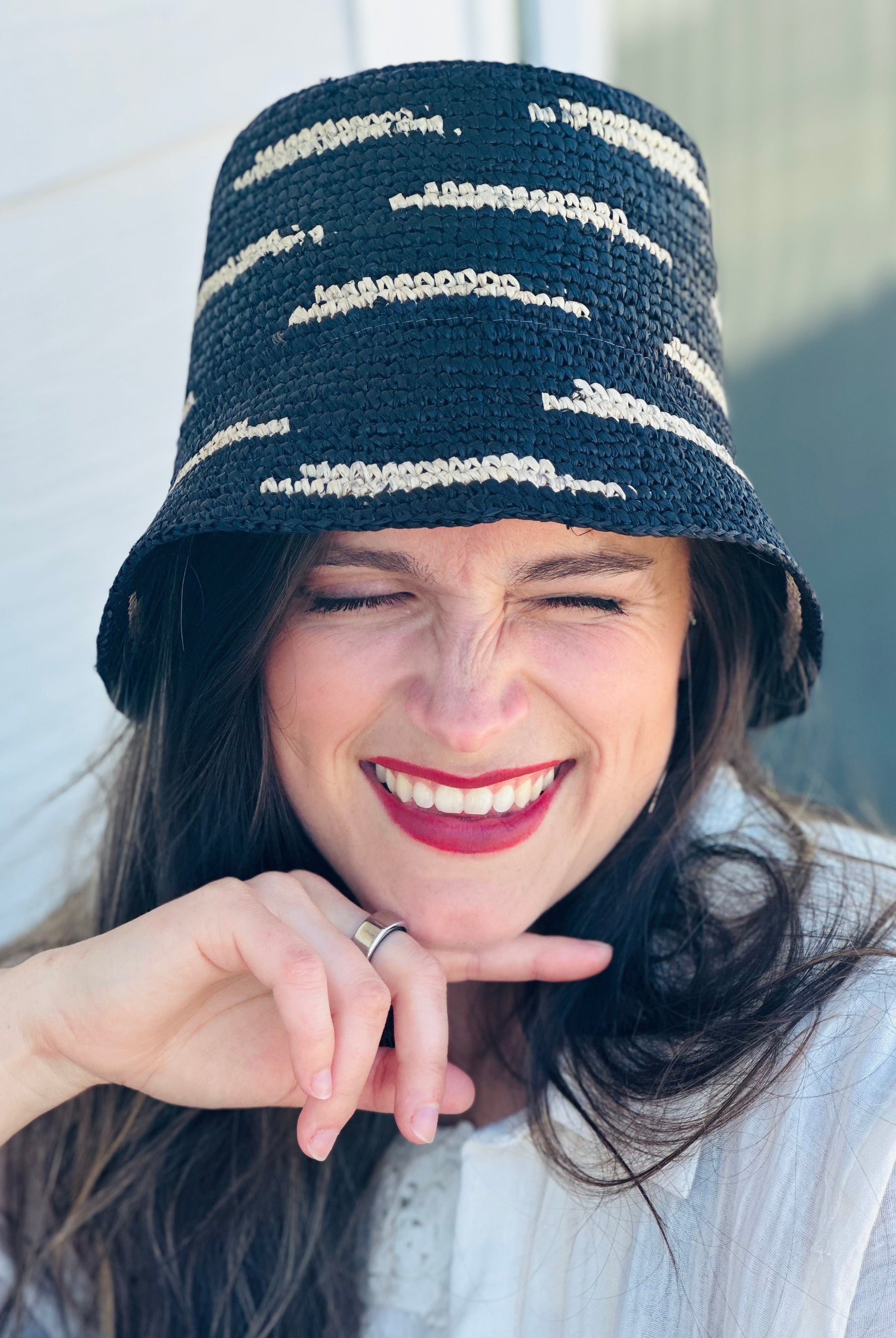 Model wearing 2.5" Brim Taylor Black Crochet Bucket Straw Hat with Zebra Stripes handmade raffia palm fiber in a two tone color combination of horizontal short stripes that create a dash pattern around the hat in black with natural straw color - Shebobo