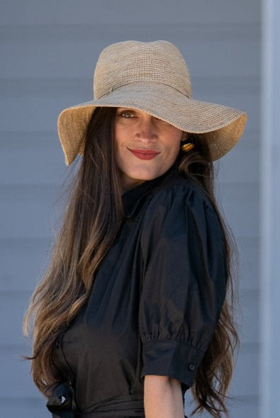 Model wearing Crochet Miramar Straw Sun Hat handmade woven raffia palm fiber in a subtle link pattered solid hue of natural straw color with matching adjustable braided hat band tie wide brim unisex panama style hat - Shebobo