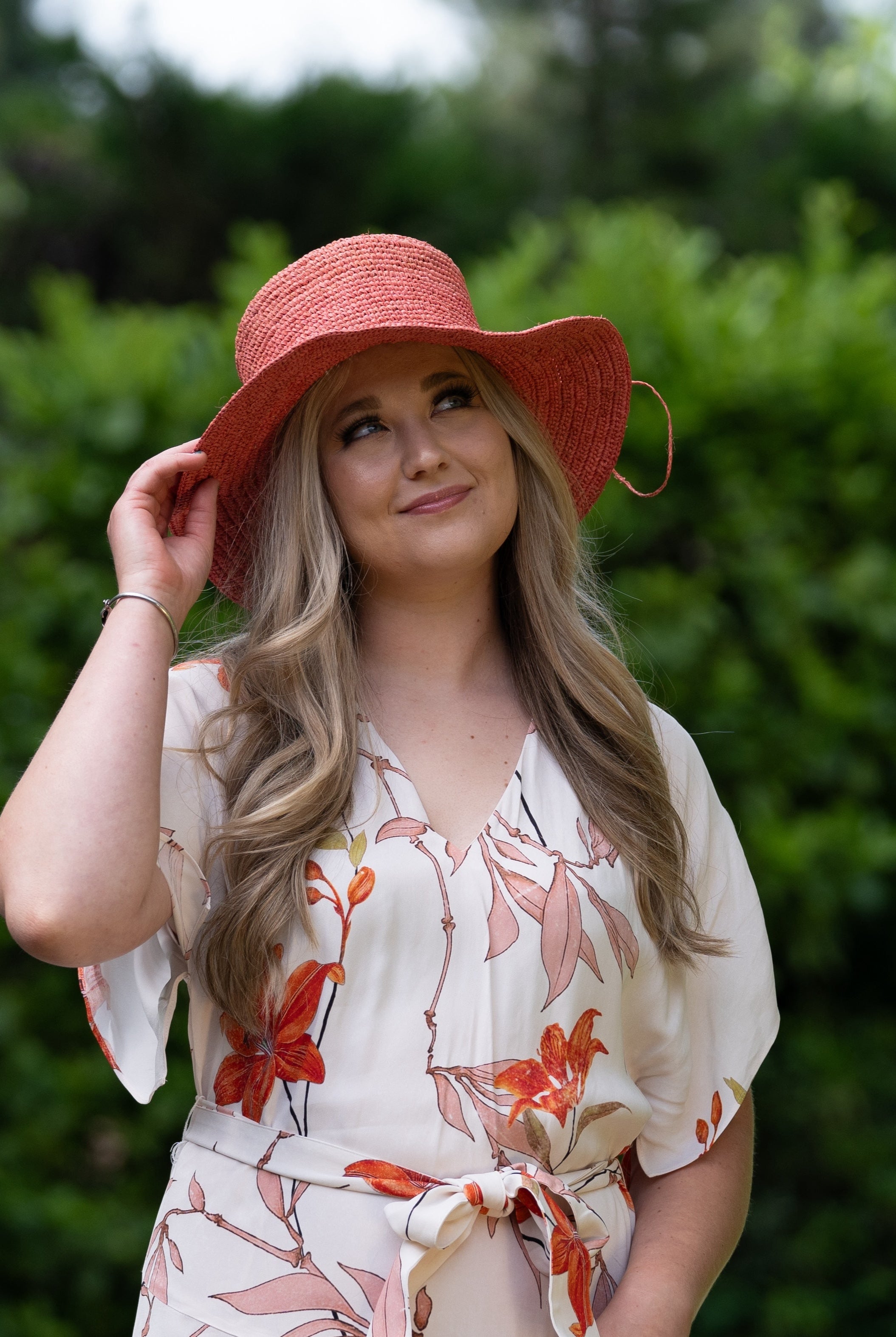 Model wearing 3" Brim Bolero Crochet Straw Sun Hats handmade crochet natural raffia palm fiber in a solid hue of Cherry Blossom pink/orange making a concentric pattern from the center top of the flattened crown spiraling out to the edge of the brim with matching adjustable raffia braid hat band - Shebobo