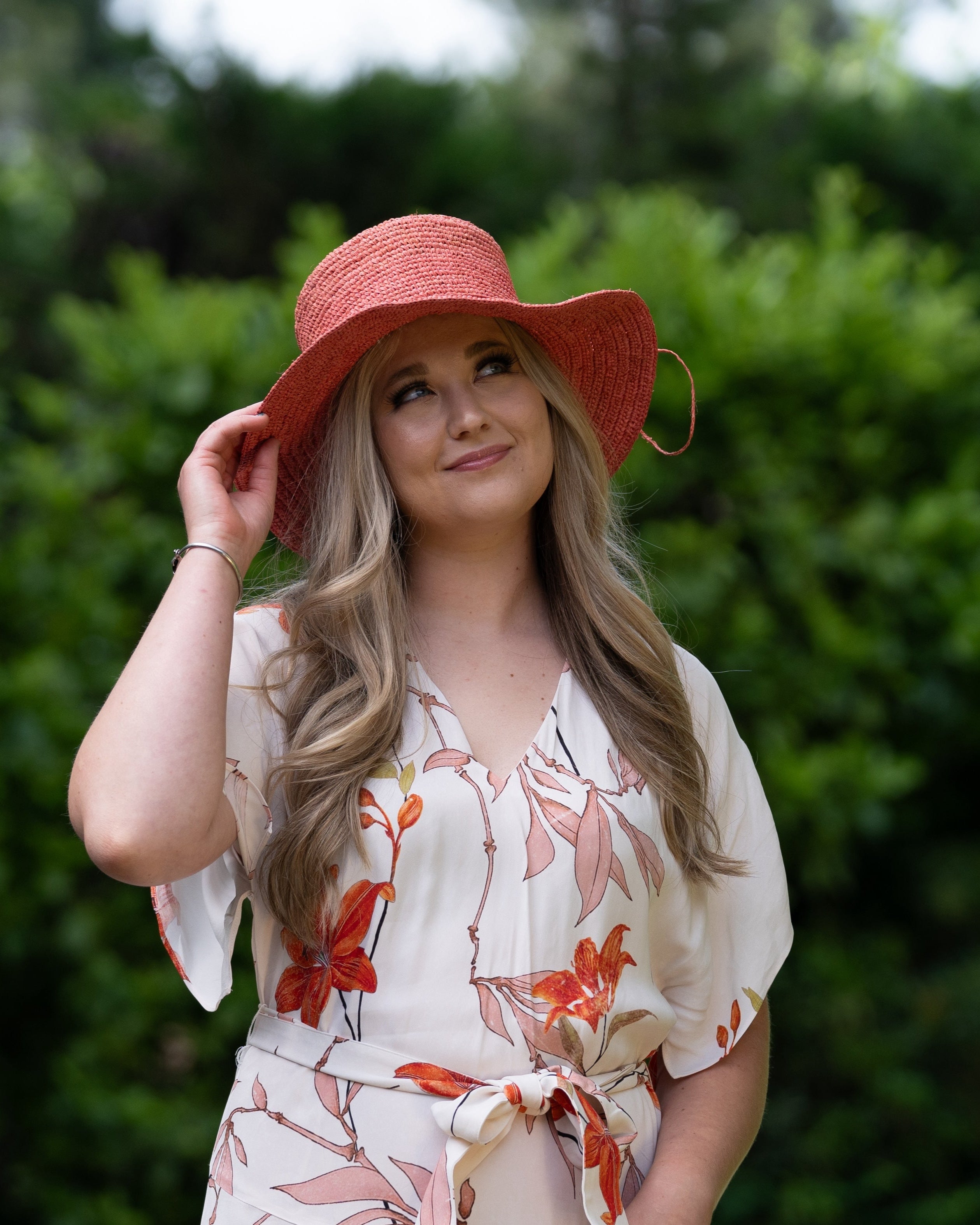 Model wearing 3" Brim Bolero Crochet Straw Sun Hats handmade crochet natural raffia palm fiber in a solid hue of Cherry Blossom pink/orange making a concentric pattern from the center top of the flattened crown spiraling out to the edge of the brim with matching adjustable raffia braid hat band - Shebobo