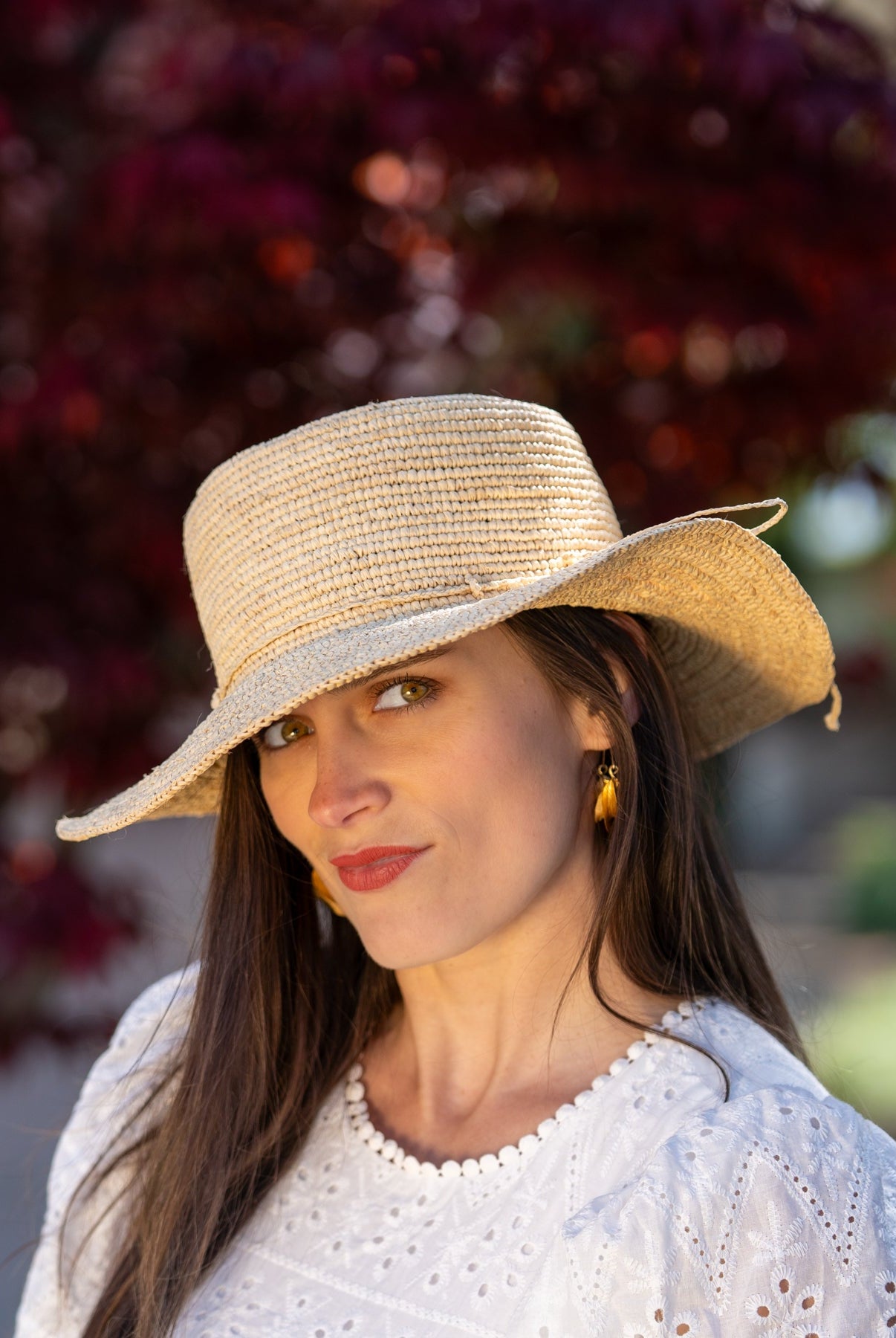 Model wearing 3" Brim Bolero Crochet Straw Sun Hats handmade crochet natural raffia palm fiber in a solid hue of natural straw color making a concentric pattern from the center top of the flattened crown spiraling out to the edge of the brim with matching adjustable raffia braid hat band - Shebobo