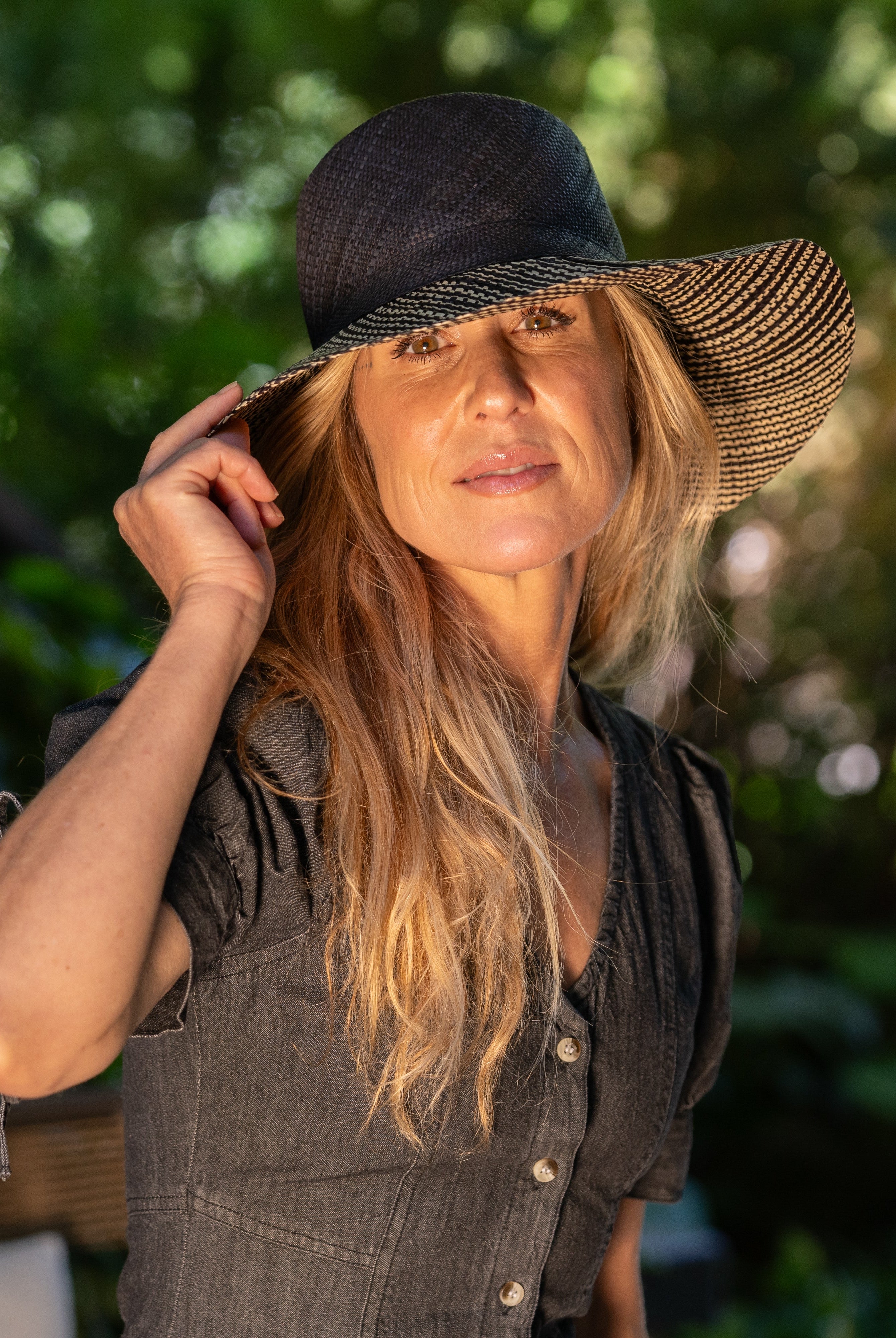 Model wearing 3" Brim Marsea Black Two Tone Melange Straw Sun Hats handmade loomed natural raffia palm fiber in a two tone color block aesthetic of solid black on the crown and hatband with multicolor melange heathered pattern swirl of black and natural straw color on the brim lightweight breathable packable hat - Shebobo