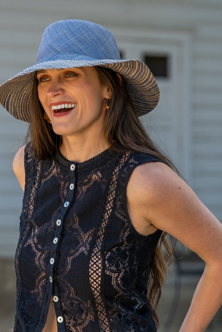 Model wearing 3" Brim Marsea Denim Two Tone Melange Straw Sun Hats handmade loomed natural raffia palm fiber in a two tone color block aesthetic of solid denim retro/light/ blue on the crown and hatband with multicolor melange heathered pattern swirl of denim and natural straw color on the brim lightweight breathable packable hat - Shebobo
