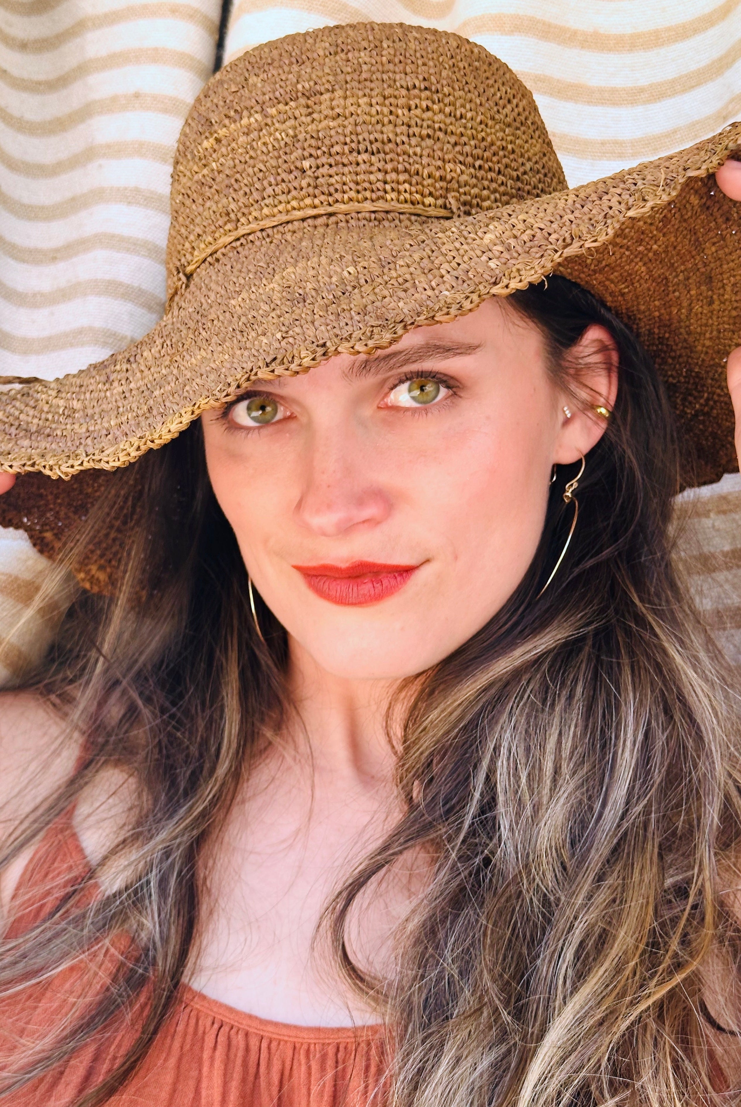 Model wearing 4" Brim Genevieve Cinnamon Crochet Straw Sun Hat with Lace Weave Edge handmade raffia palm fiber crochet solid hue cinammon/tobacco/brown rounded crown with detailed lace weave edge and matching adjustable hat band - Shebobo