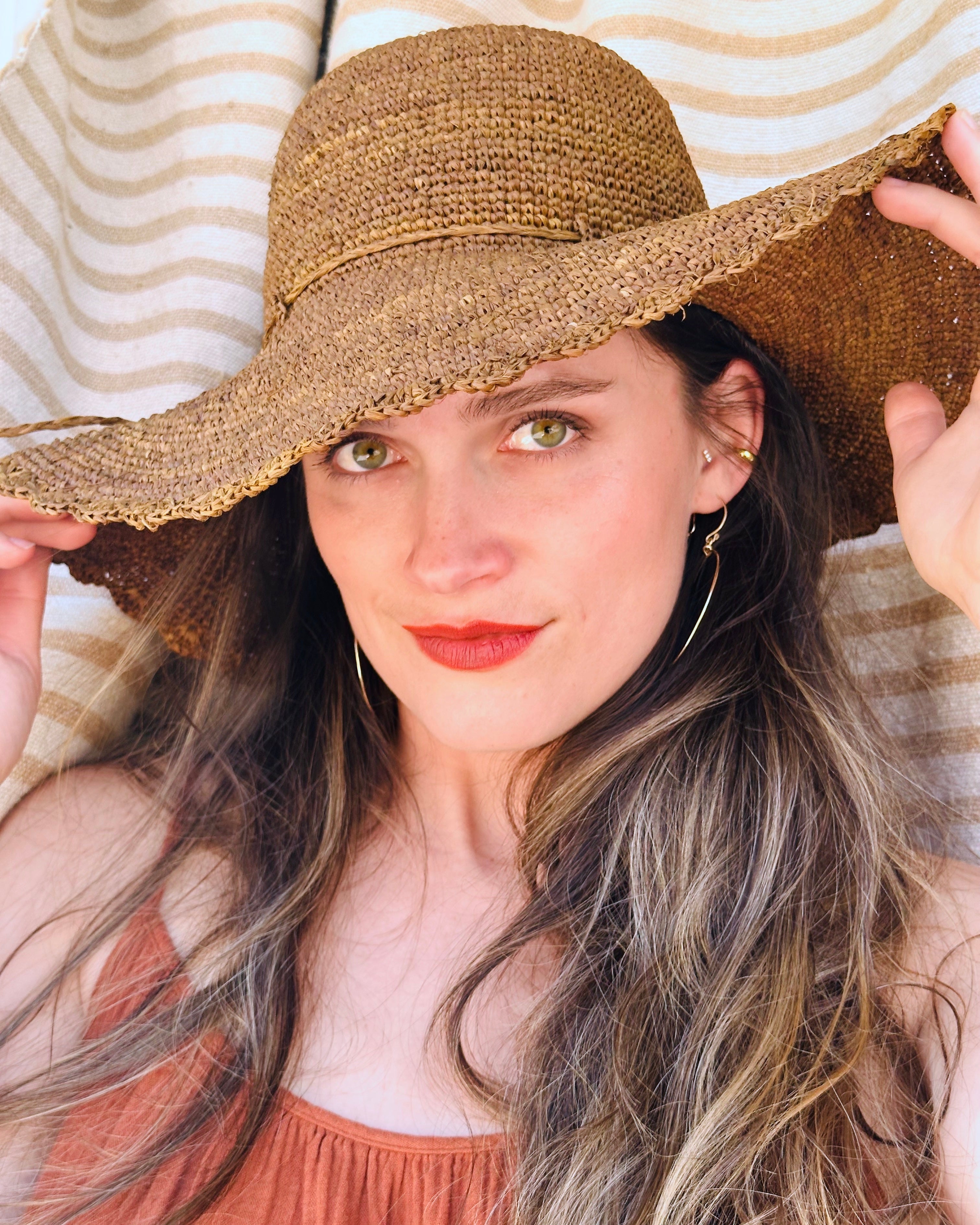 Model wearing 4" Brim Genevieve Cinnamon Crochet Straw Sun Hat with Lace Weave Edge handmade raffia palm fiber crochet solid hue cinammon/tobacco/brown rounded crown with detailed lace weave edge and matching adjustable hat band - Shebobo