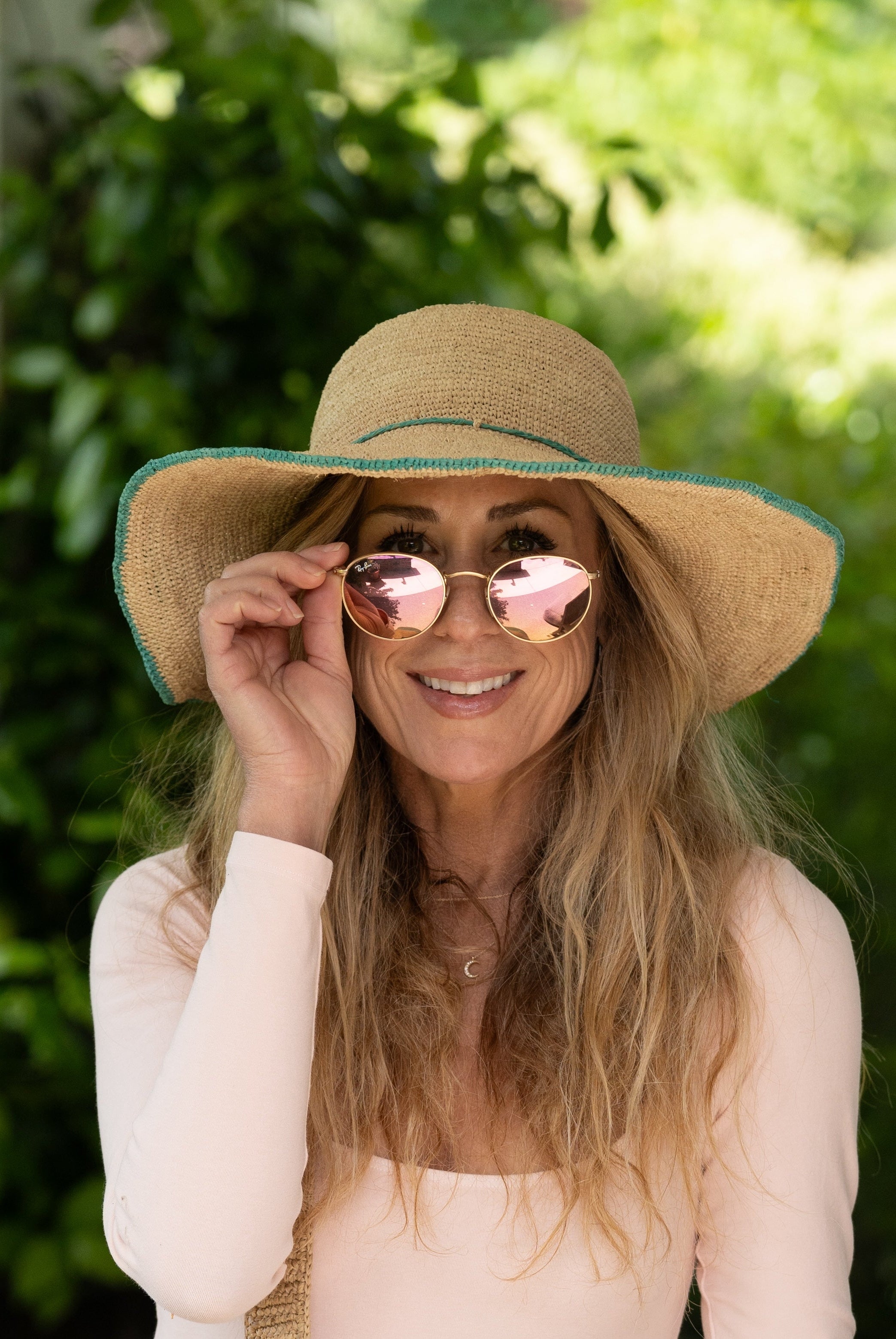 Model wearing 4" Brim Rachel Seafoam Crochet Straw Sun Hat handmade crochet natural raffia hat with seafoam blue/green edge and matching corded hat band - Shebobo