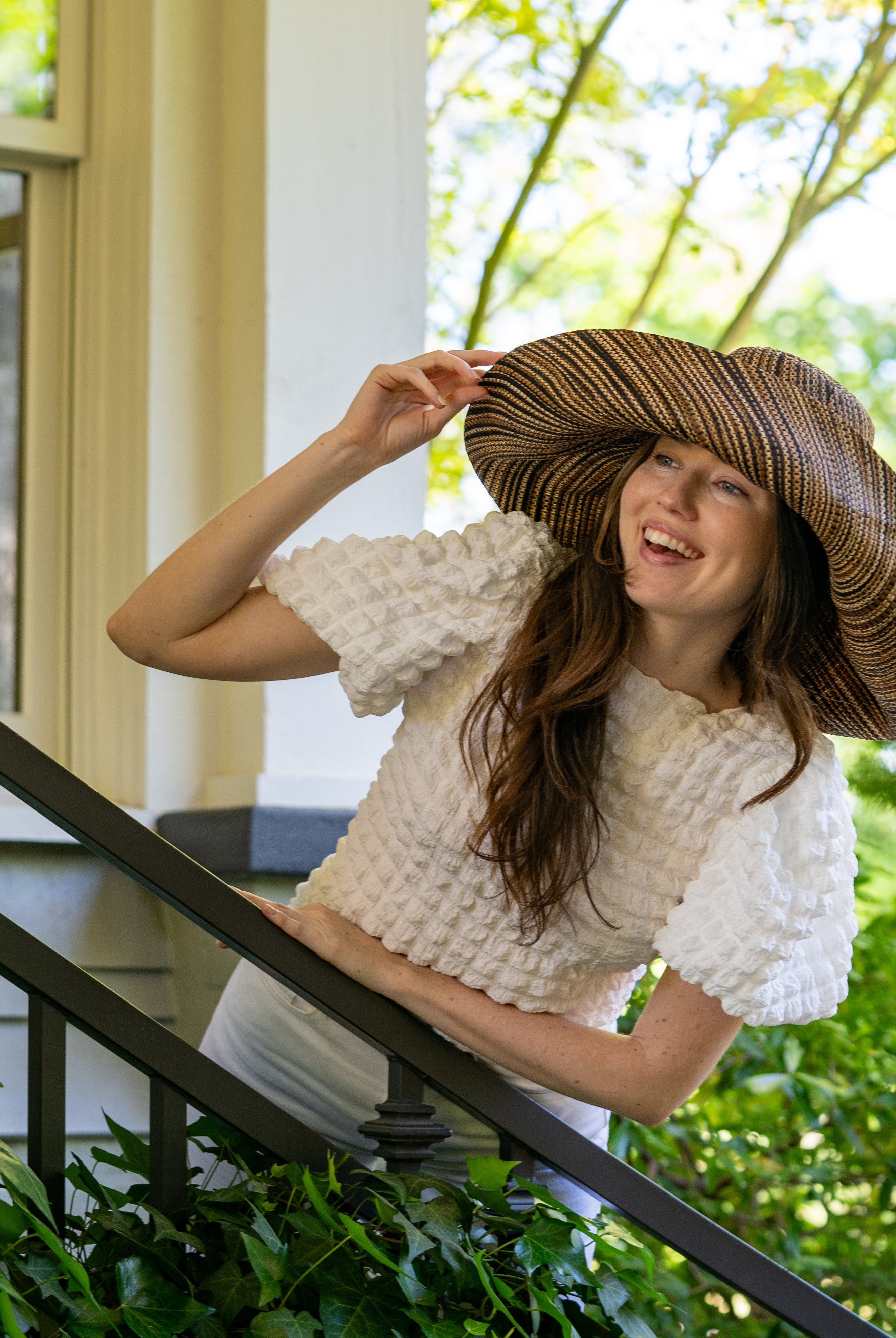 Model wearing 7" Wide Brim Cinnamon Multi Melange Packable Straw Sun Hat handmade loomed raffia in a heathered swirl pattern of multiple tones of natural, brown, and black - Shebobo