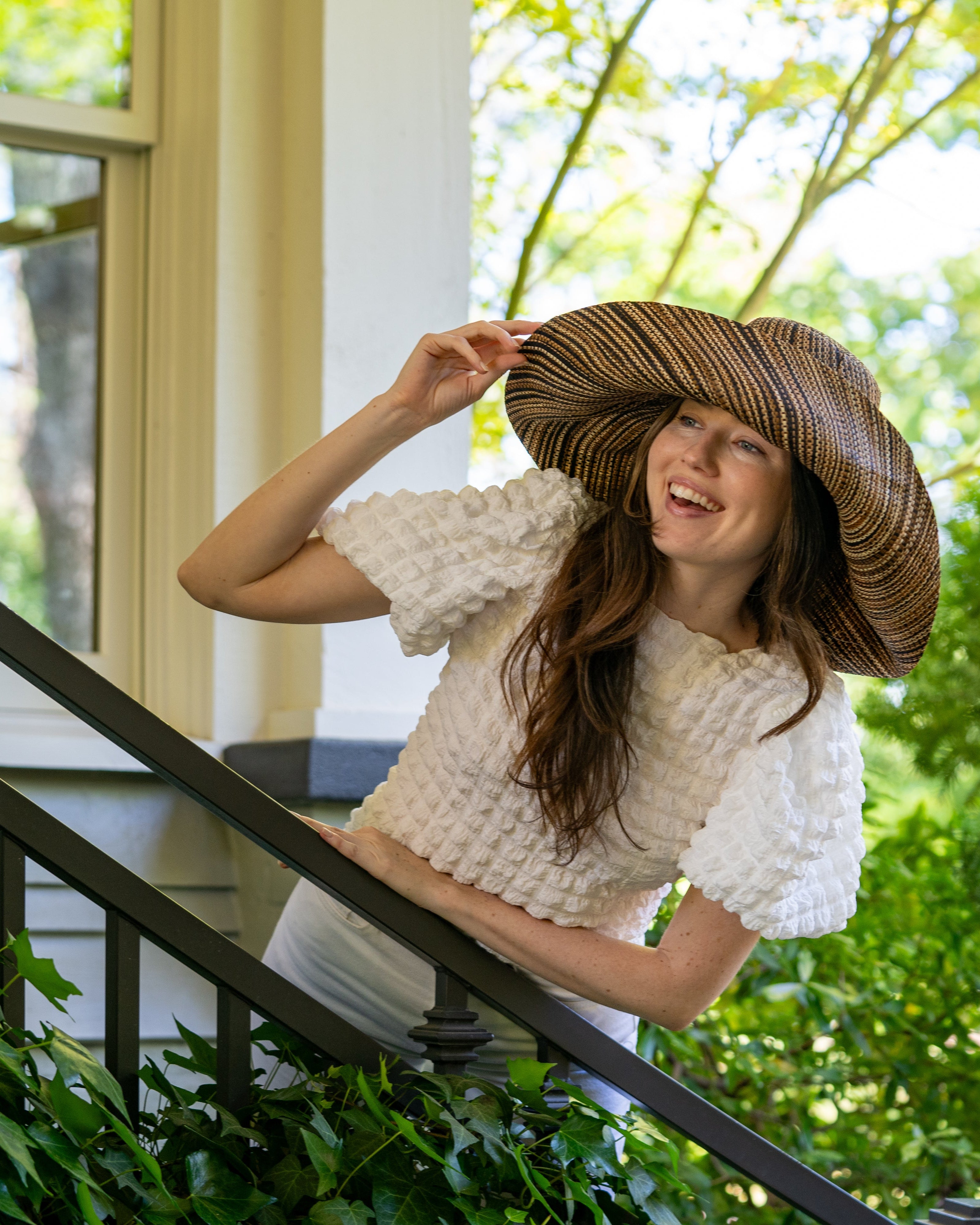 Model wearing 7" Wide Brim Cinnamon Multi Melange Packable Straw Sun Hat handmade loomed raffia in a heathered swirl pattern of multiple tones of natural, brown, and black - Shebobo