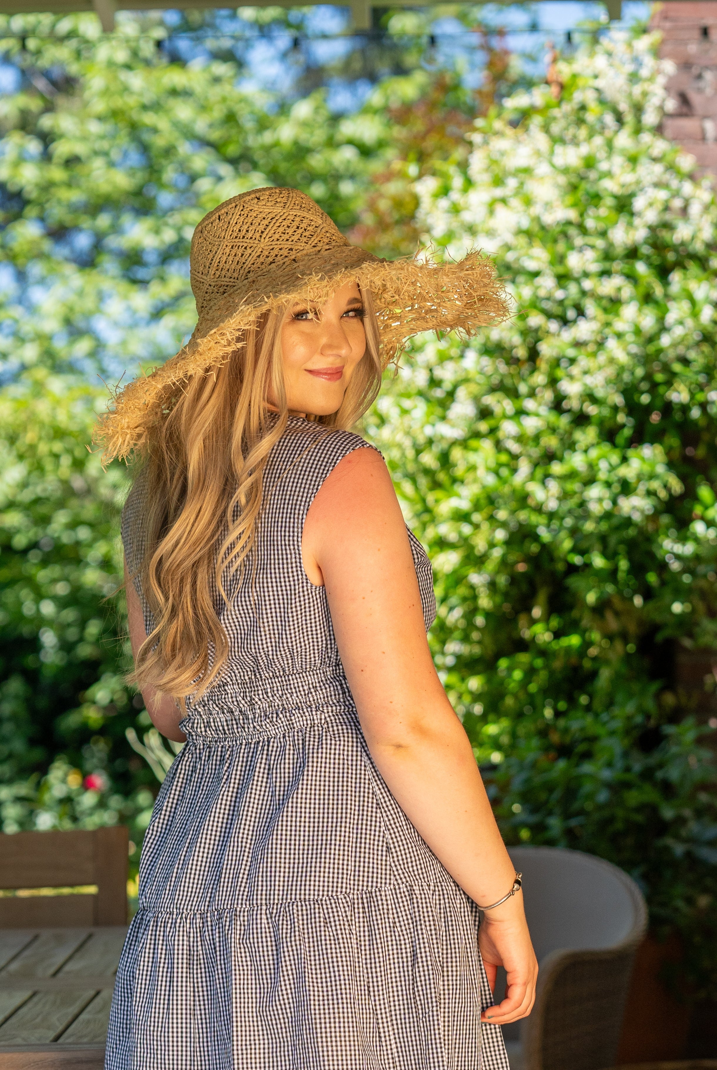Model wearing Karin Crochet & Macrame Natural Raffia Knotted Straw Sun Hat Lightweight Breathable with Fringe Edge geometric star or sunburst design brim and geometric knotted diamond pattern top - Shebobo