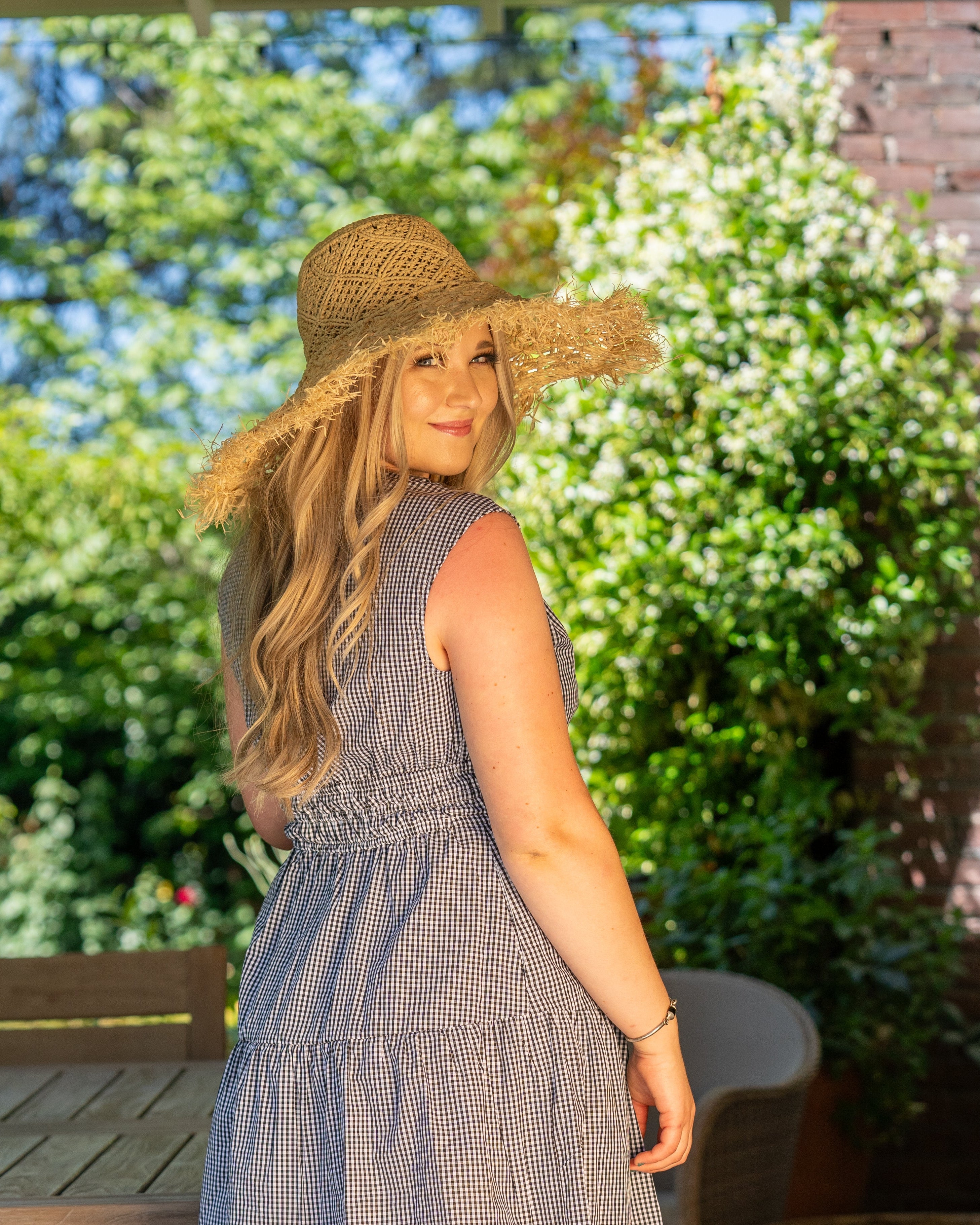 Model wearing Karin Crochet & Macrame Natural Raffia Knotted Straw Sun Hat Lightweight Breathable with Fringe Edge geometric star or sunburst design brim and geometric knotted diamond pattern top - Shebobo