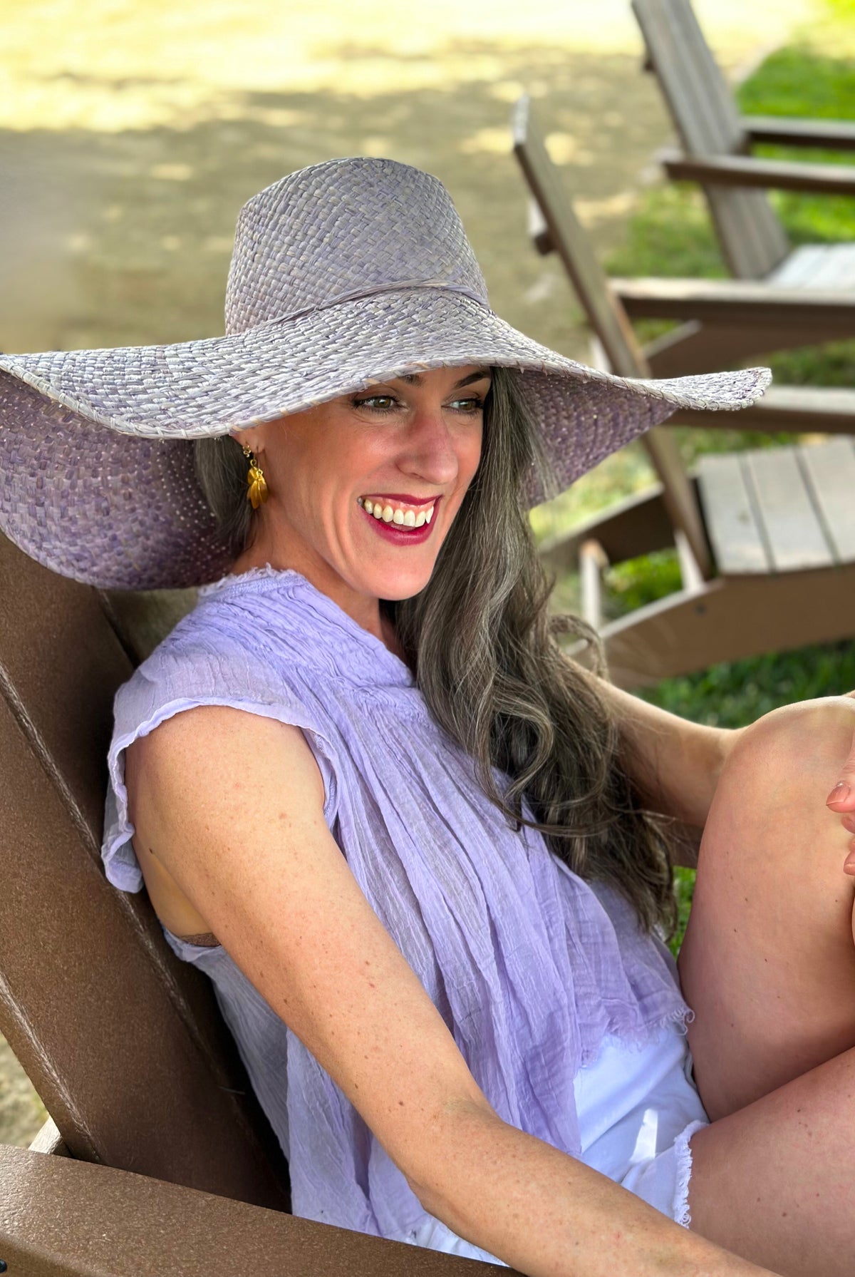 Model wearing 7" Brim Natasha Wisteria Woven XL Straw Sun Hat handmade woven natural raffia palm fiber in a solid hue of wisteria/lavender/lilac pink/purple with matching adjustable twisted raffia hat band and and extra wide brim - Shebobo