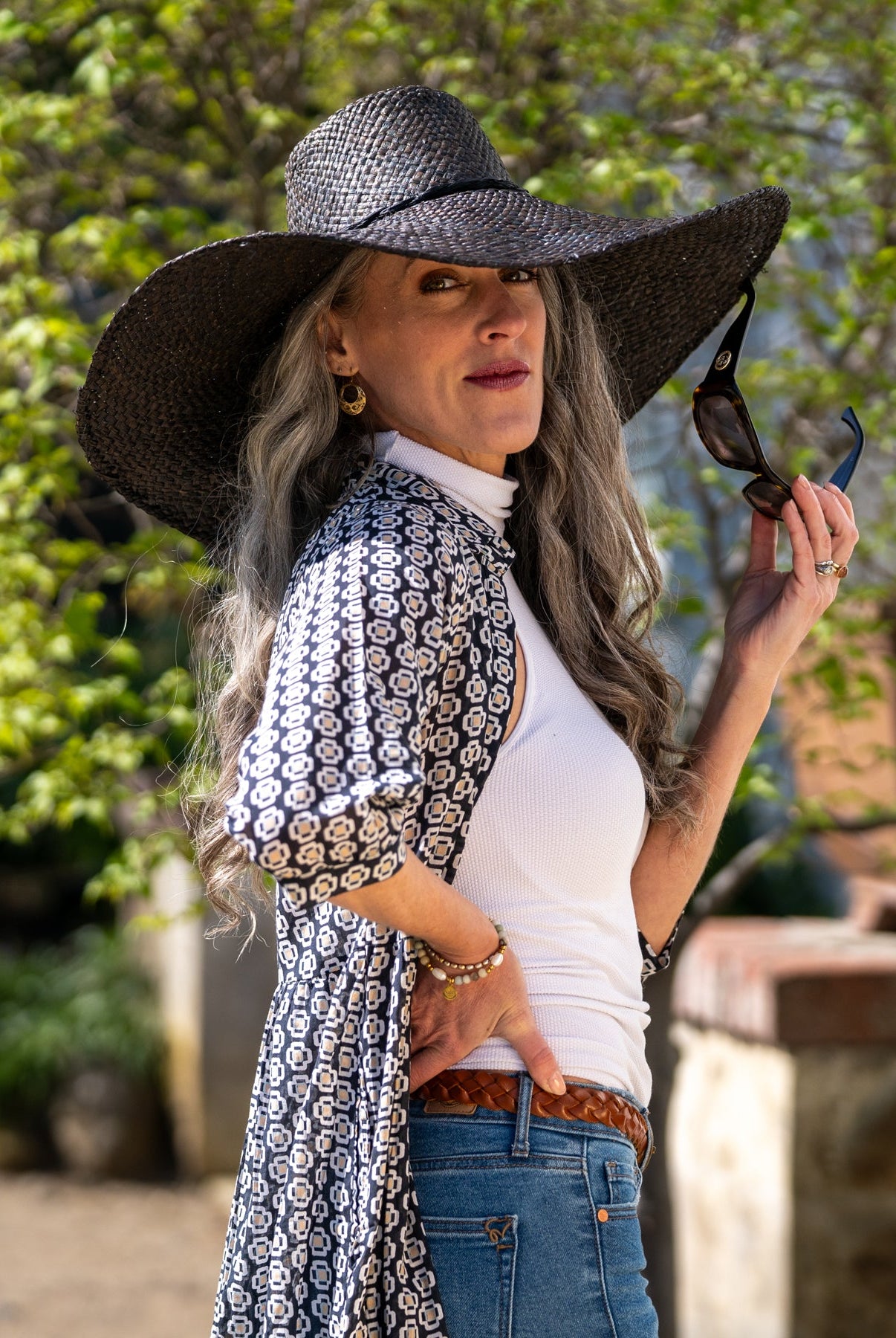 Model wearing 7" Wide Brim Natasha Black Woven XL Straw Sun Hat handmade woven natural raffia palm fiber in a solid hue of black with matching adjustable twisted raffia hat band and and extra wide brim - Shebobo
