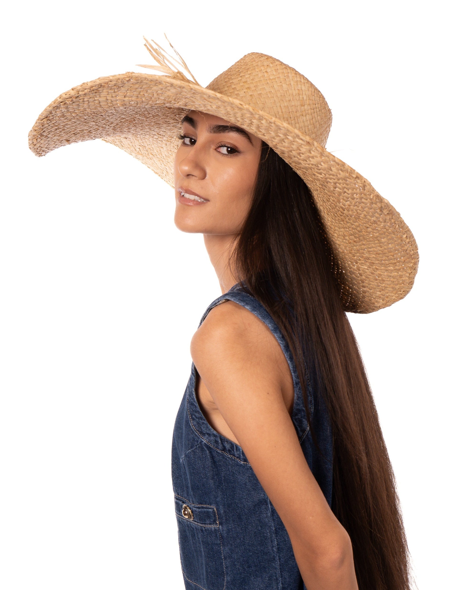 Model wearing 7" Wide Brim Natasha Natural Woven XL Straw Sun Hat handmade woven natural raffia palm fiber in a solid hue of straw color with matching adjustable twisted raffia hat band and and extra wide brim - Shebobo