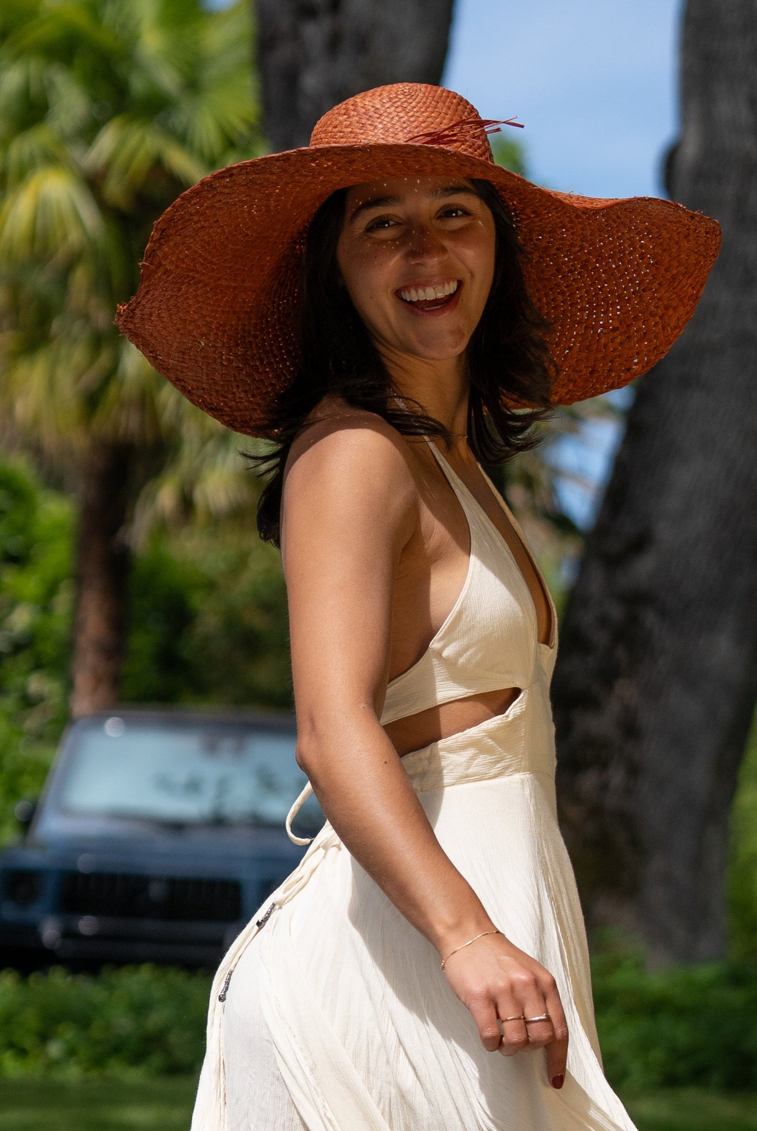 Model wearing 7" Wide Brim Natasha Caramel Woven XL Straw Sun Hat handmade woven natural raffia palm fiber in a solid hue of whisky red/brown with matching adjustable twisted raffia hat band and and extra wide brim - Shebobo