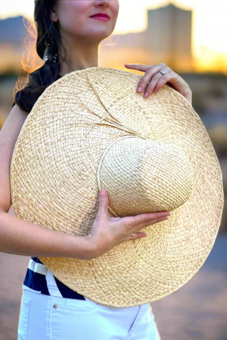 Model wearing 7" Wide Brim Natasha Natural Woven XL Straw Sun Hat handmade woven natural raffia palm fiber in a solid hue of straw color with matching adjustable twisted raffia hat band and and extra wide brim - Shebobo