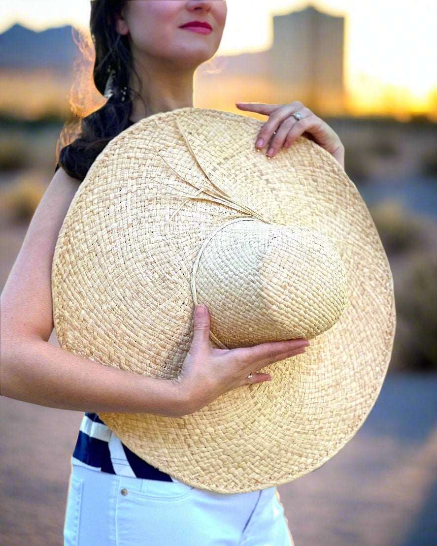 Model wearing 7" Wide Brim Natasha Natural Woven XL Straw Sun Hat handmade woven natural raffia palm fiber in a solid hue of straw color with matching adjustable twisted raffia hat band and and extra wide brim - Shebobo