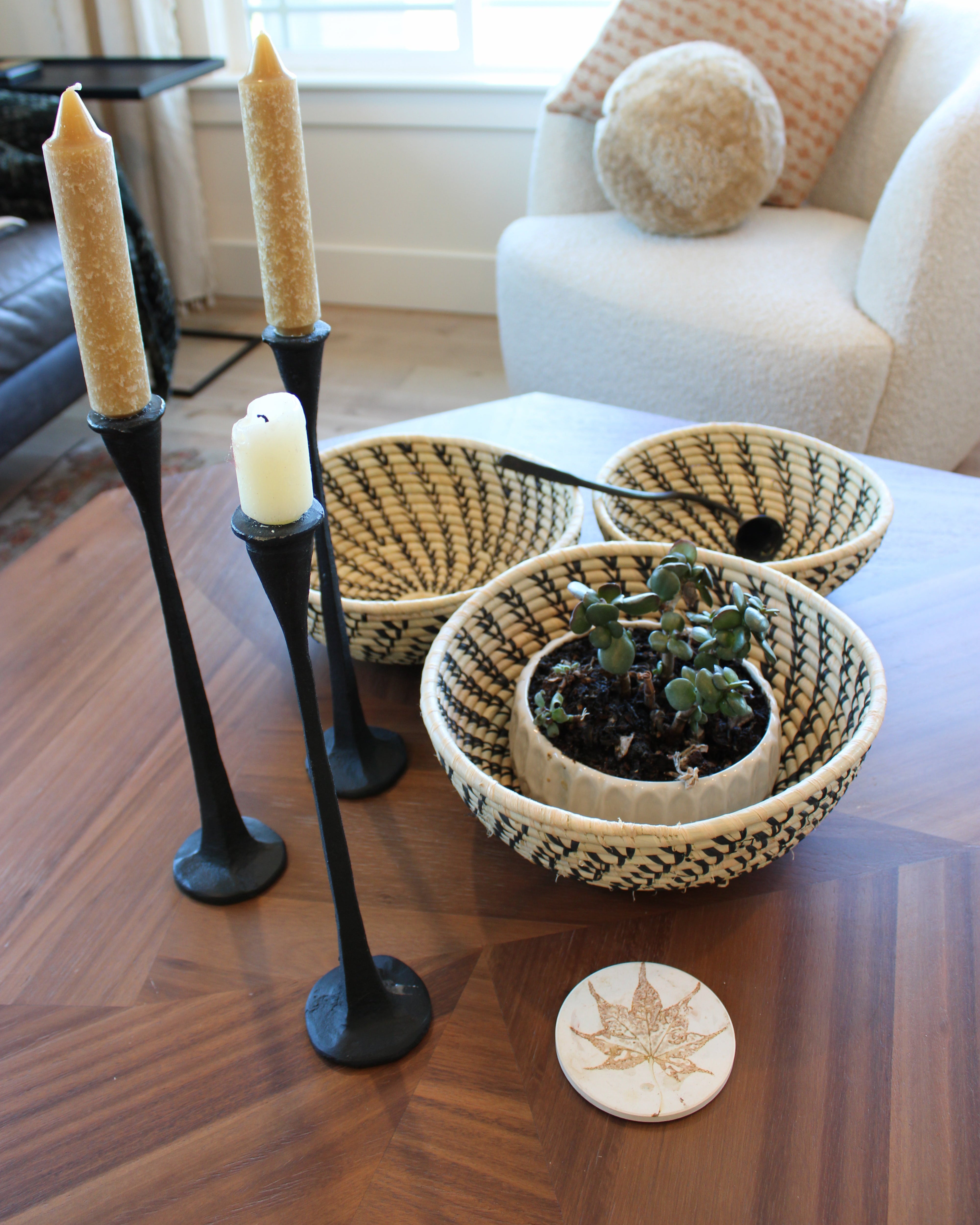 Home decor lifestyle view Amara Raffia Straw Decor Display Basket Bowls: Set of 3 handmade woven natural raffia palm fiber in a crochet loop technique concentric coiled circular pattern with natural straw color centered in the bottom and that go up the sides of the bowls with contrasting black swirl stitch pattern and matching natural rim/edge set of small, medium, and large straw display bowls - Shebobo