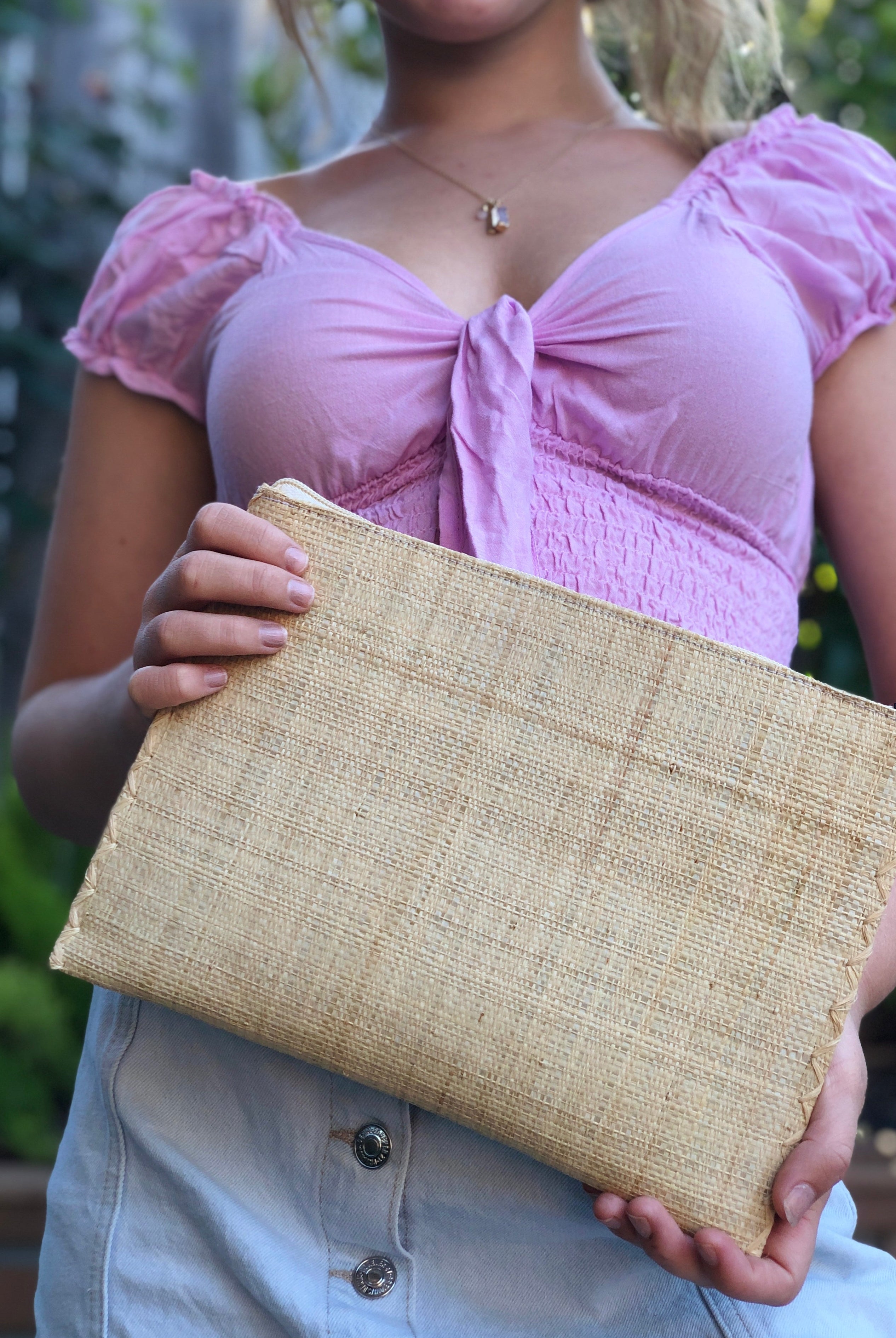 Model wearing Amelia size large of Set of 3 Natural straw color Nesting Zippered Straw Clutches Solid Colors handmade loomed raffia in a solid hue with matching zipper and braided zipper pull with cross stitch edging in three sizes of small, medium, and large - Shebobo