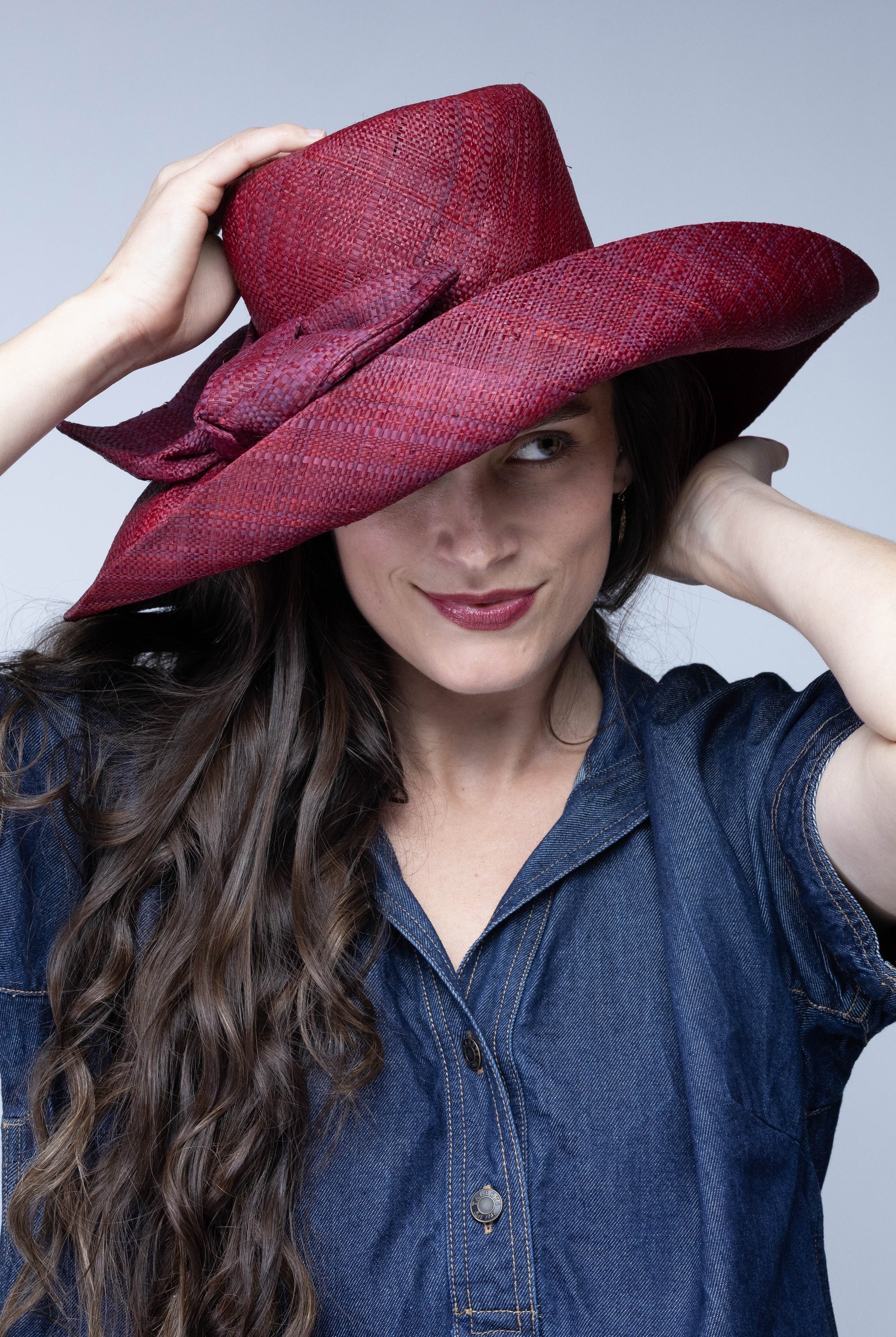 Model wearing Audrey 5" Wide Brim Solid Color Straw Sun Hats with Big Bow handmade loomed natural raffia straw fiber in a solid hue of Umberwine bordeaux/claret/deep/dark/red/purple with matching oversized big bow embellishment hat band - Shebobo