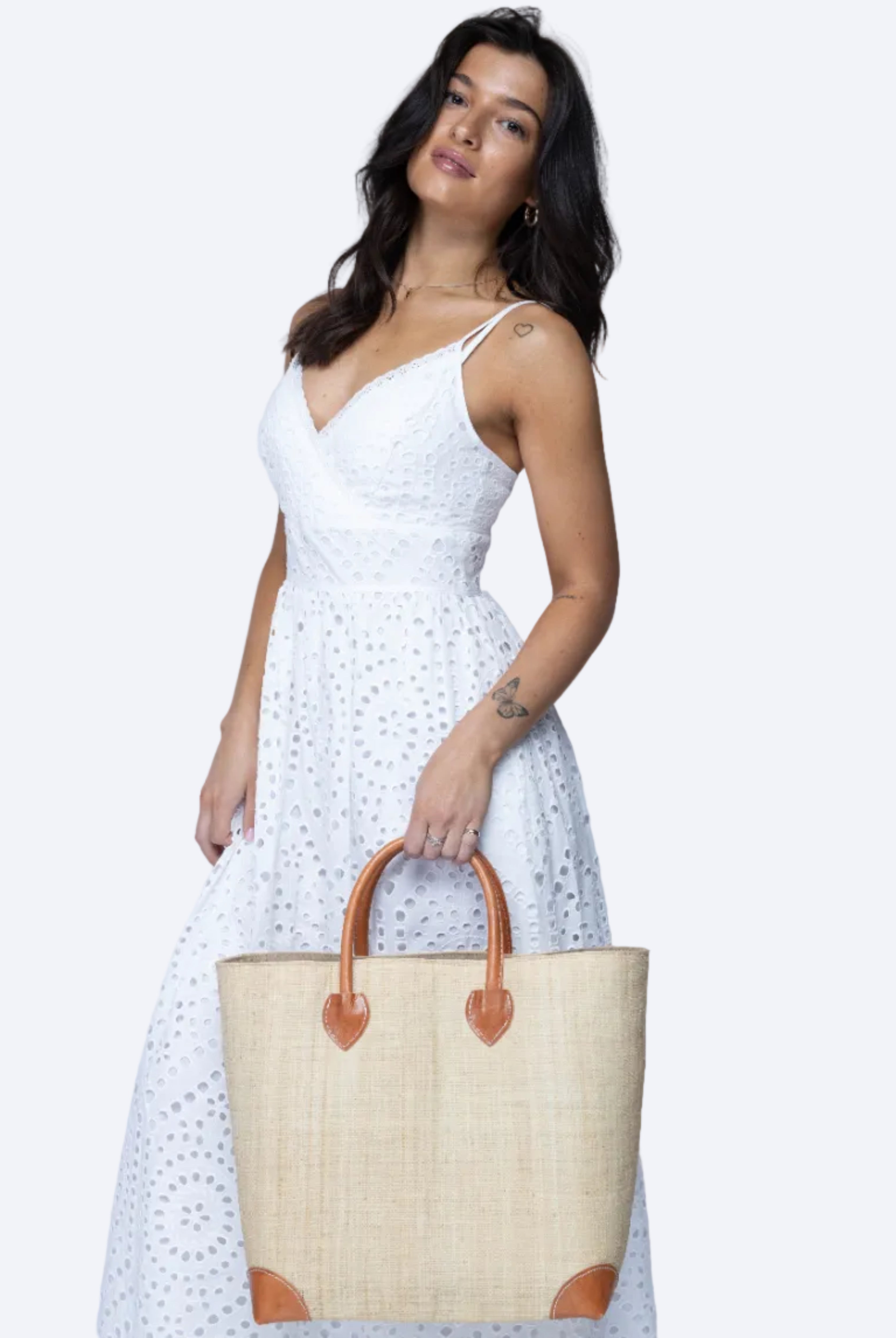 Model wearing Large Augustine Straw Basket Bag Natural handmade loomed raffia palm fiber in a solid hue of natural straw color handbag purse with leather accents and handles beach bag - Shebobo