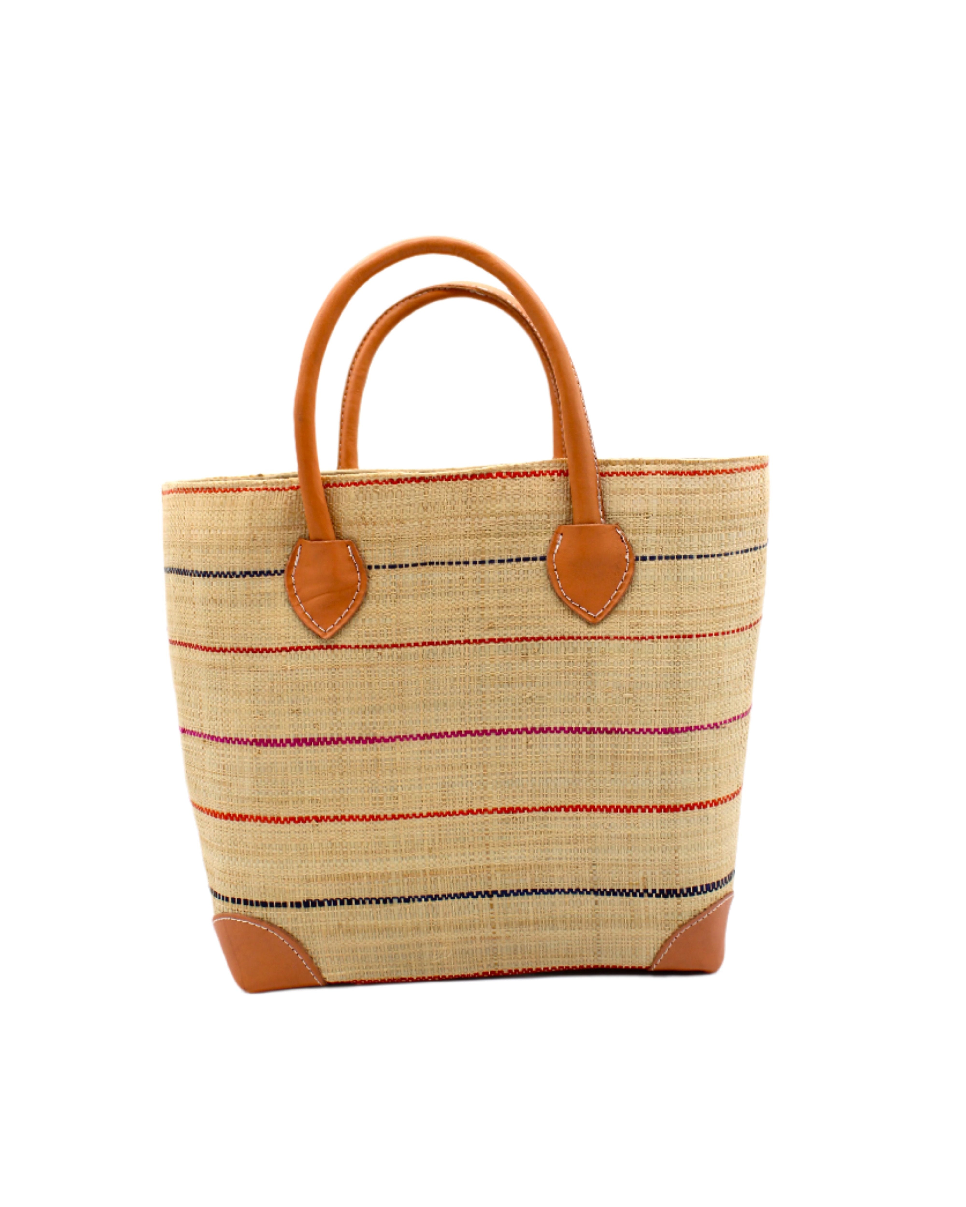Augustine pinstripes straw basket bag handmade loomed raffia in natural wide horizontal bands with multicolor coral red/orange, fuchsia pink, and navy blue small bands running through in a stripe pattern with leather accents and handles handbag purse - Shebobo