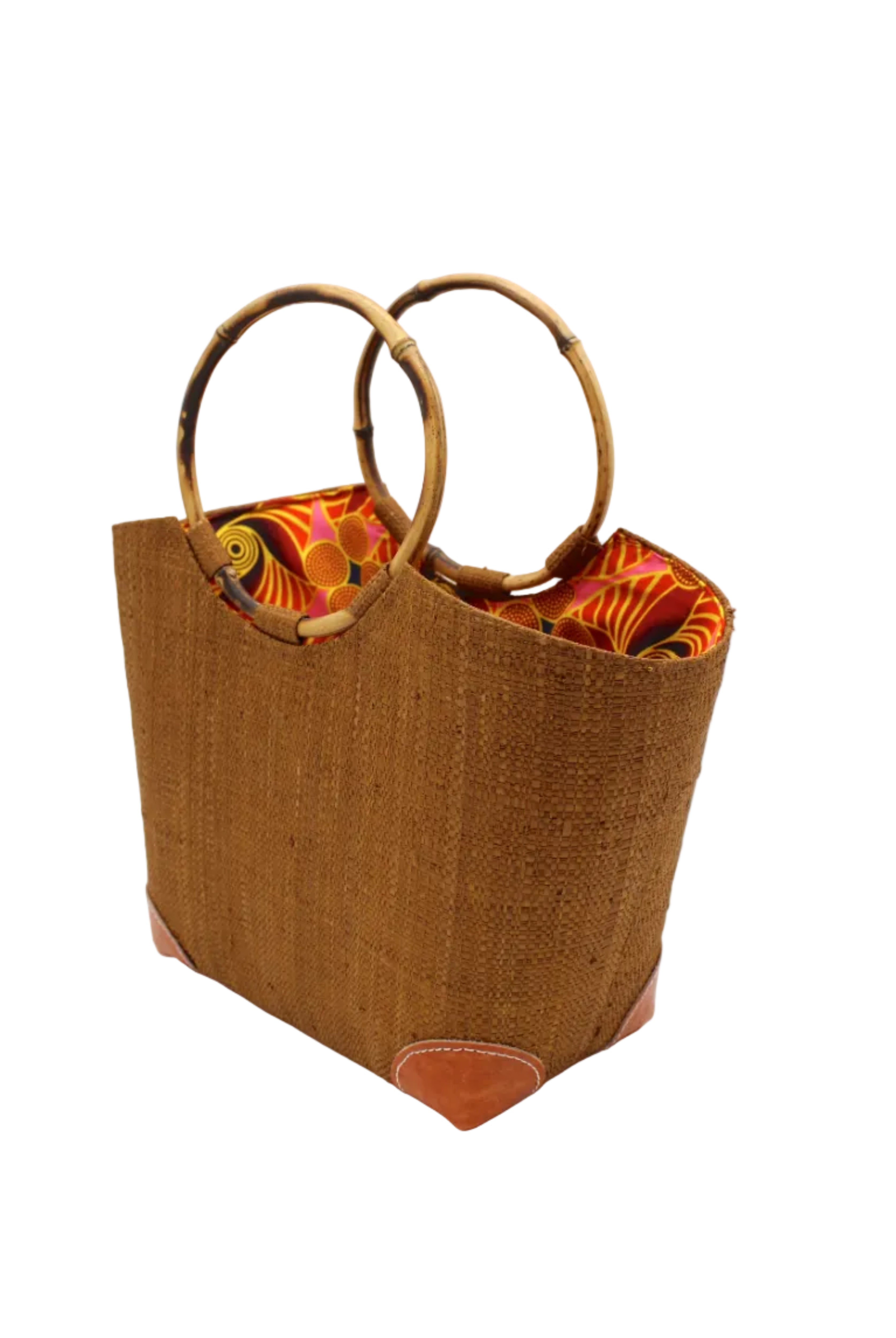 Side view Betty Straw Bucket Bag with Bamboo Handles handmade loomed natural raffia palm fiber in a solid hue of tobacco cinnamon/dark/brown with circular bamboo handles, leather feet, and colorful African Print wax cloth liner handbag purse tote - Shebobo
