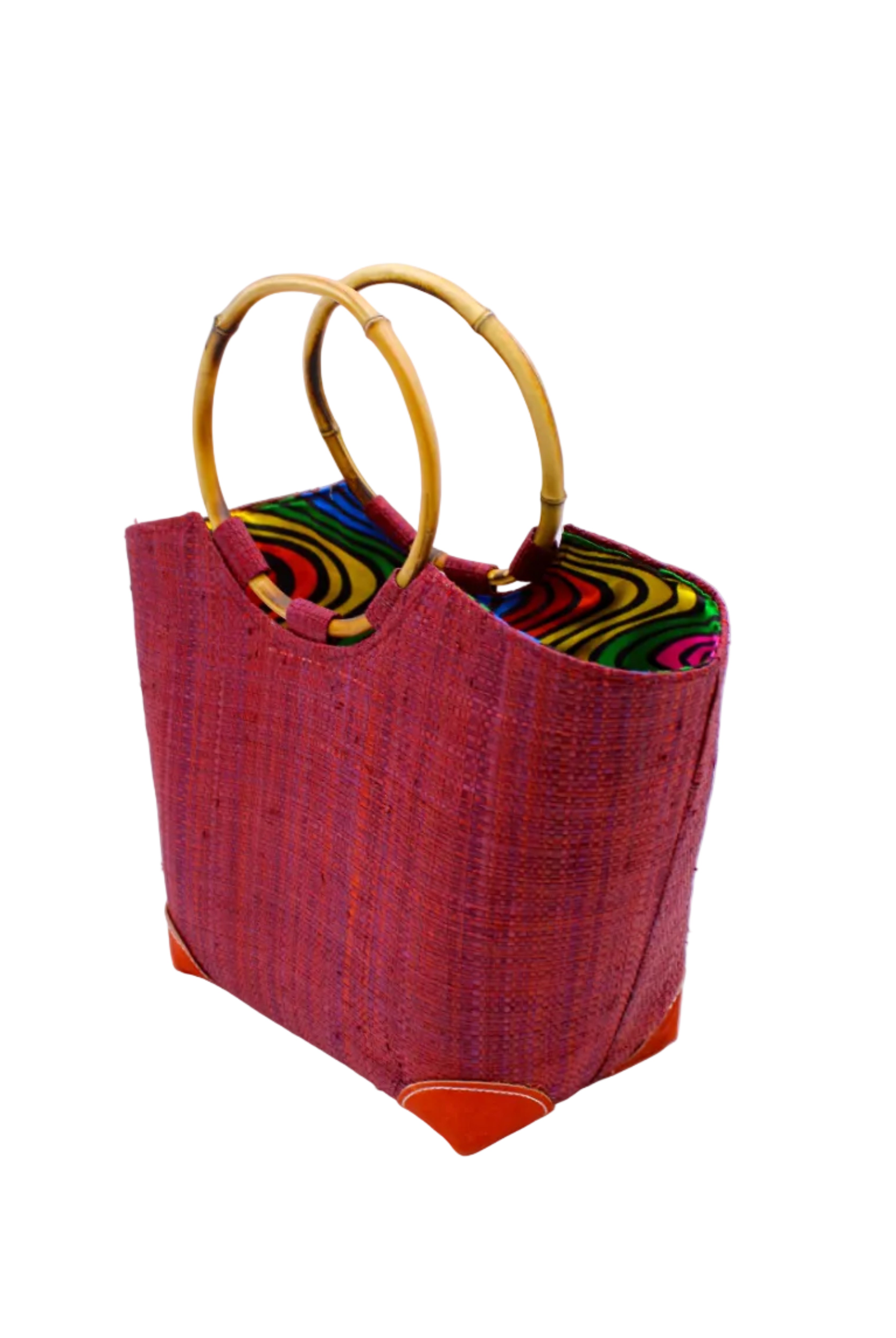 Side view Betty Straw Bucket Bag with Bamboo Handles handmade loomed natural raffia palm fiber in a solid hue of umberwine burgundy/dark/purple/red with circular bamboo handles, leather feet, and colorful African Print wax cloth liner handbag purse tote - Shebobo