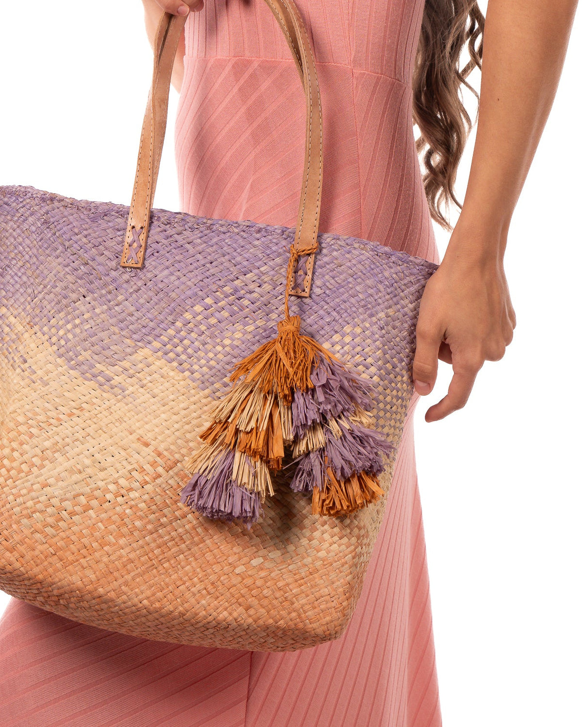 Model wearing Tassels Layered Raffia Tufts Charm Embellishment Blush Multi handmade knotted and brushed natural raffia palm fiber in a multicolor layered tuft tassel of blush light/orange/pink, natural straw color, and lilas lilac/wisteria/light/purple beach bag handbag charm embellishment or party decor - Shebobo