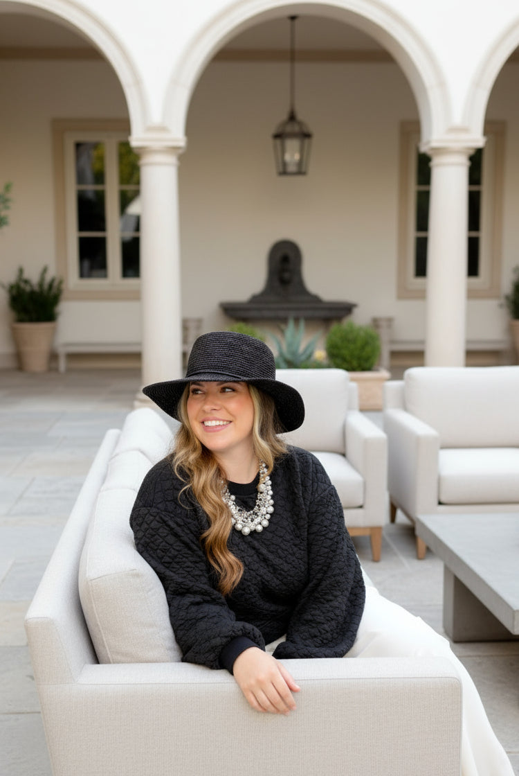 Model wearing 3" Brim Bolero Crochet Straw Sun Hats handmade crochet natural raffia palm fiber in a solid hue of black making a concentric pattern from the center top of the flattened crown spiraling out to the edge of the brim with matching adjustable raffia braid hat band - Shebobo