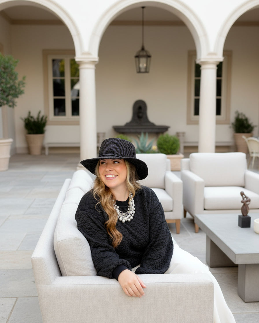 Model wearing 3" Brim Bolero Crochet Straw Sun Hats handmade crochet natural raffia palm fiber in a solid hue of black making a concentric pattern from the center top of the flattened crown spiraling out to the edge of the brim with matching adjustable raffia braid hat band - Shebobo