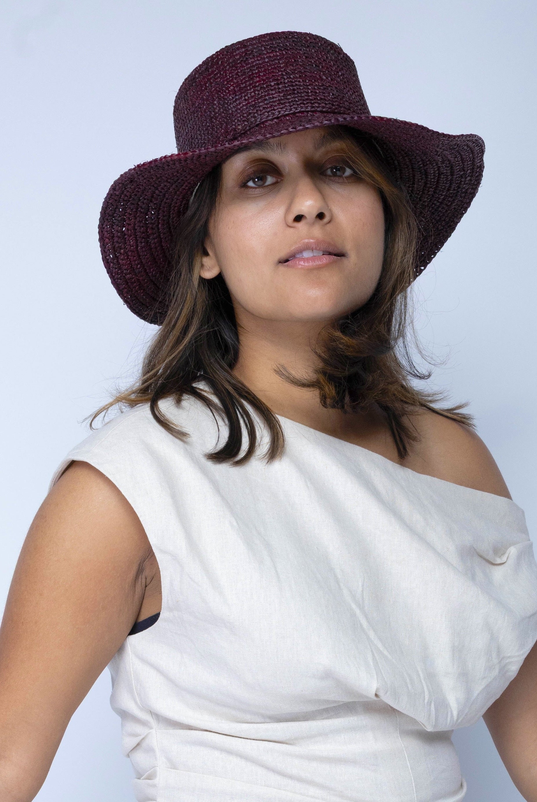 Model wearing 3" Brim Bolero Crochet Straw Sun Hats handmade crochet natural raffia palm fiber in a solid hue of mocha dark/chocolate/brown making a concentric pattern from the center top of the flattened crown spiraling out to the edge of the brim with matching adjustable raffia braid hat band - Shebobo