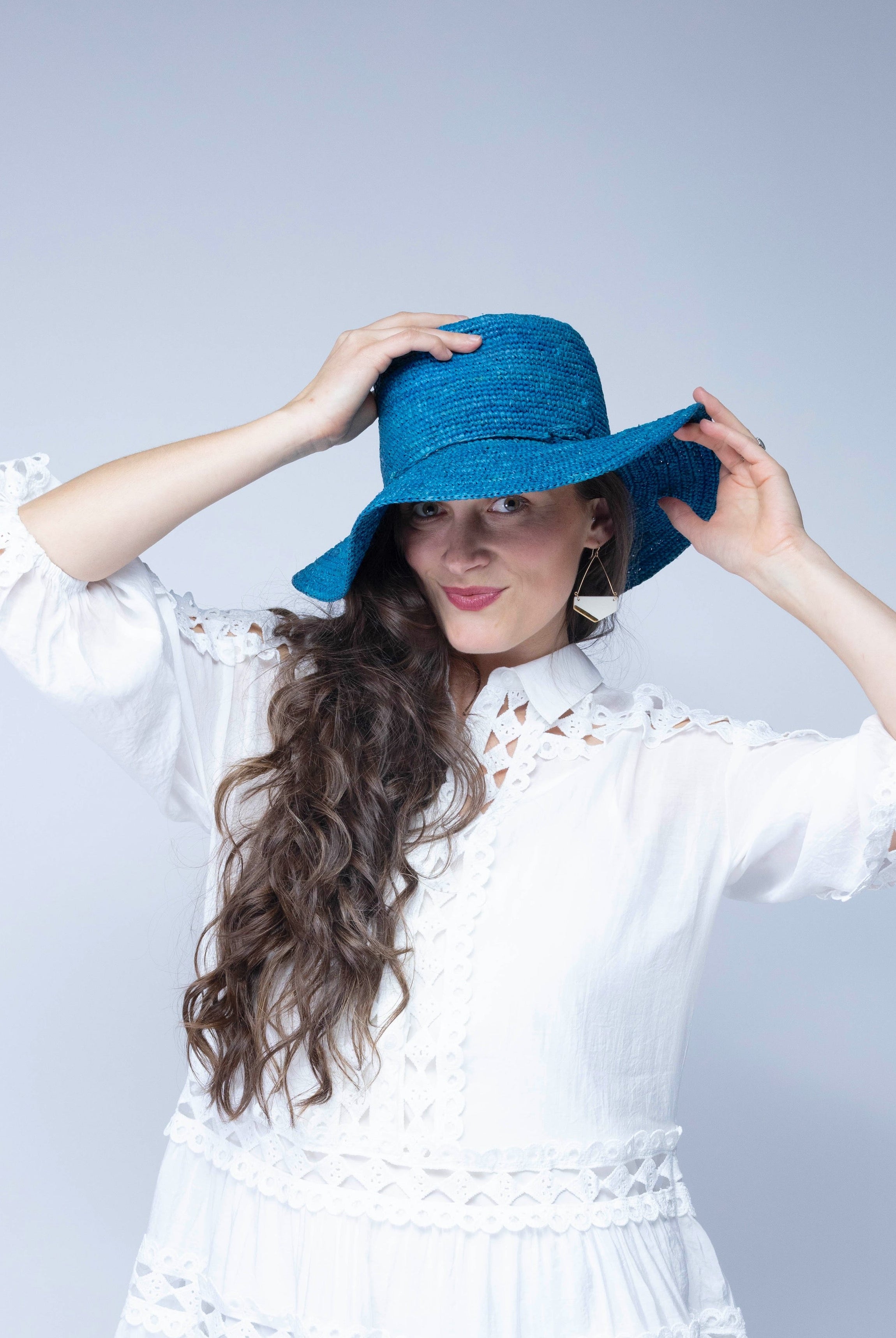 Model wearing 3" Brim Bolero Crochet Straw Sun Hats handmade crochet natural raffia palm fiber in a solid hue of turquoise blue/green making a concentric pattern from the center top of the flattened crown spiraling out to the edge of the brim with matching adjustable raffia braid hat band - Shebobo