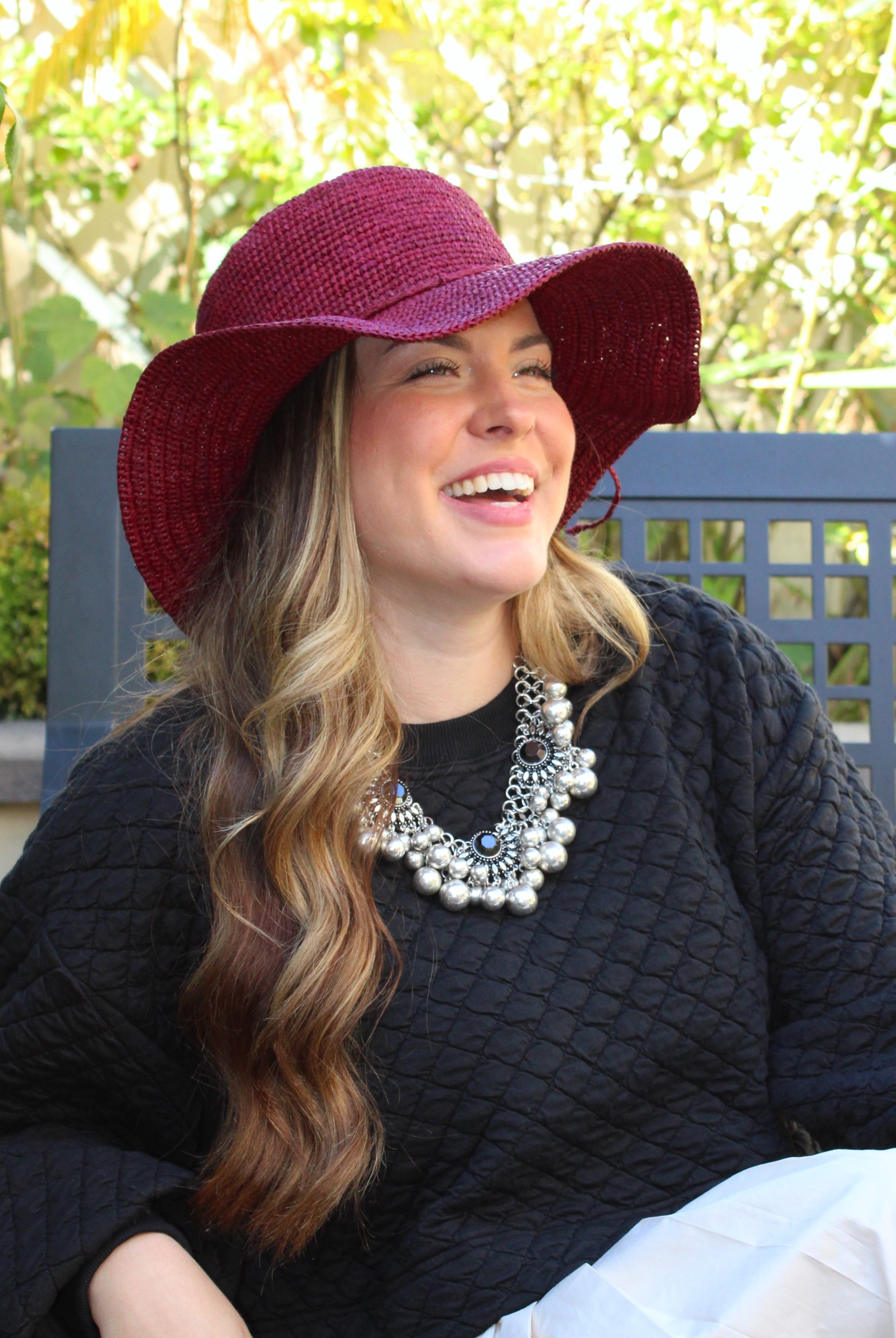 Model wearing 3" Brim Bolero Crochet Straw Sun Hats handmade crochet natural raffia palm fiber in a solid hue of umberwine bordeaux/claret/deep/dark/red/purple making a concentric pattern from the center top of the flattened crown spiraling out to the edge of the brim with matching adjustable raffia braid hat band - Shebobo