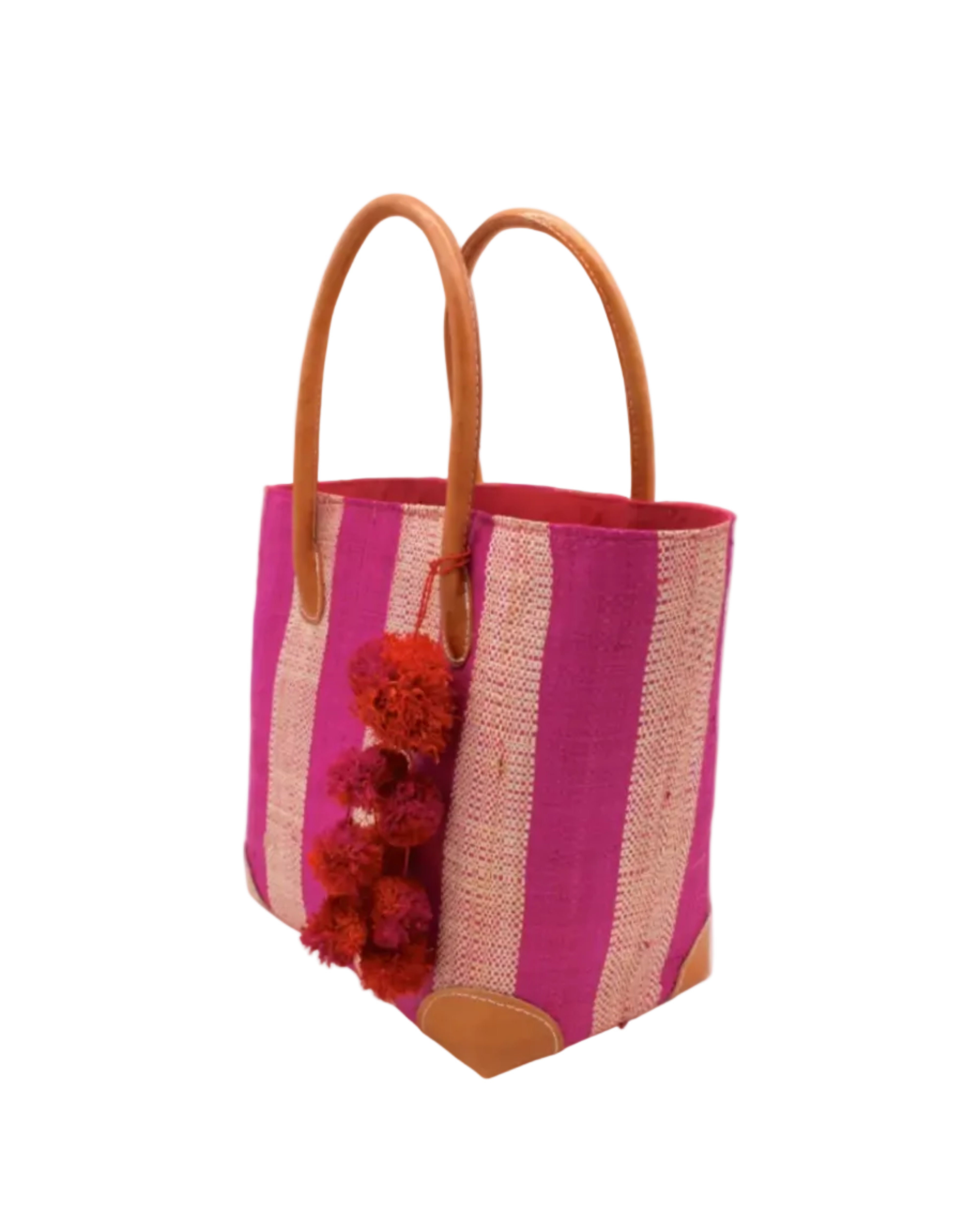 Side view Bora Bora Fuchsia Two Tone Stripes Straw Basket Bag with Waterfall Pompoms Charm Embellishment handmade loomed natural raffia palm fiber in a multicolor horizontal stripe pattern of even width wide bands of fuchsia hot/bright/barbie/pink and natural straw color with leather handles and feet plus matching waterfall pompom charm embellishment handbag beach bag - Shebobo