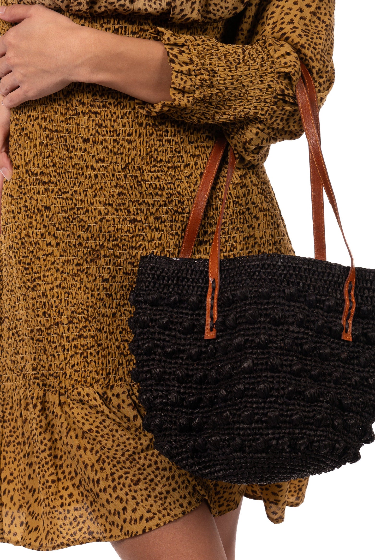 Model wearing Boucle Black Crochet Small Straw Handbag handmade woven raffia palm fiber in a solid hue of black in a supple nub/ball texture of horizontal bands around the bag with link weave around the top plus assorted print drawstring liner and leather handles shoulder bag purse - Shebobo