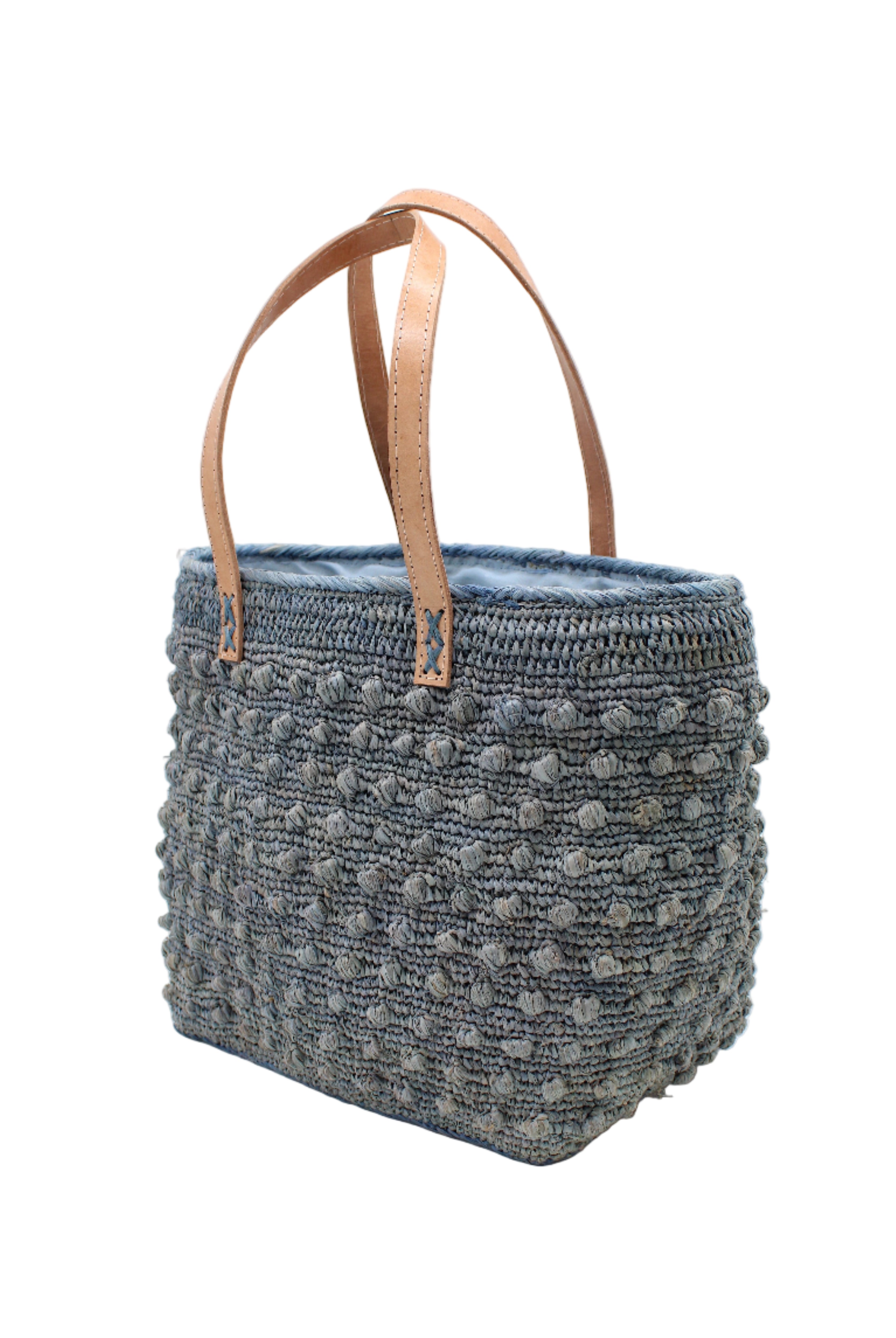 Side view Boucle Denim Crochet Straw Basket Bag handmade woven raffia palm fiber in a solid hue of denim retro/light/blue in a supple nub/ball texture of horizontal bands around the bag with link weave around the top and loop crochet edging on the bottom and top plus leather handles beach bag shoulder bag purse - Shebobo