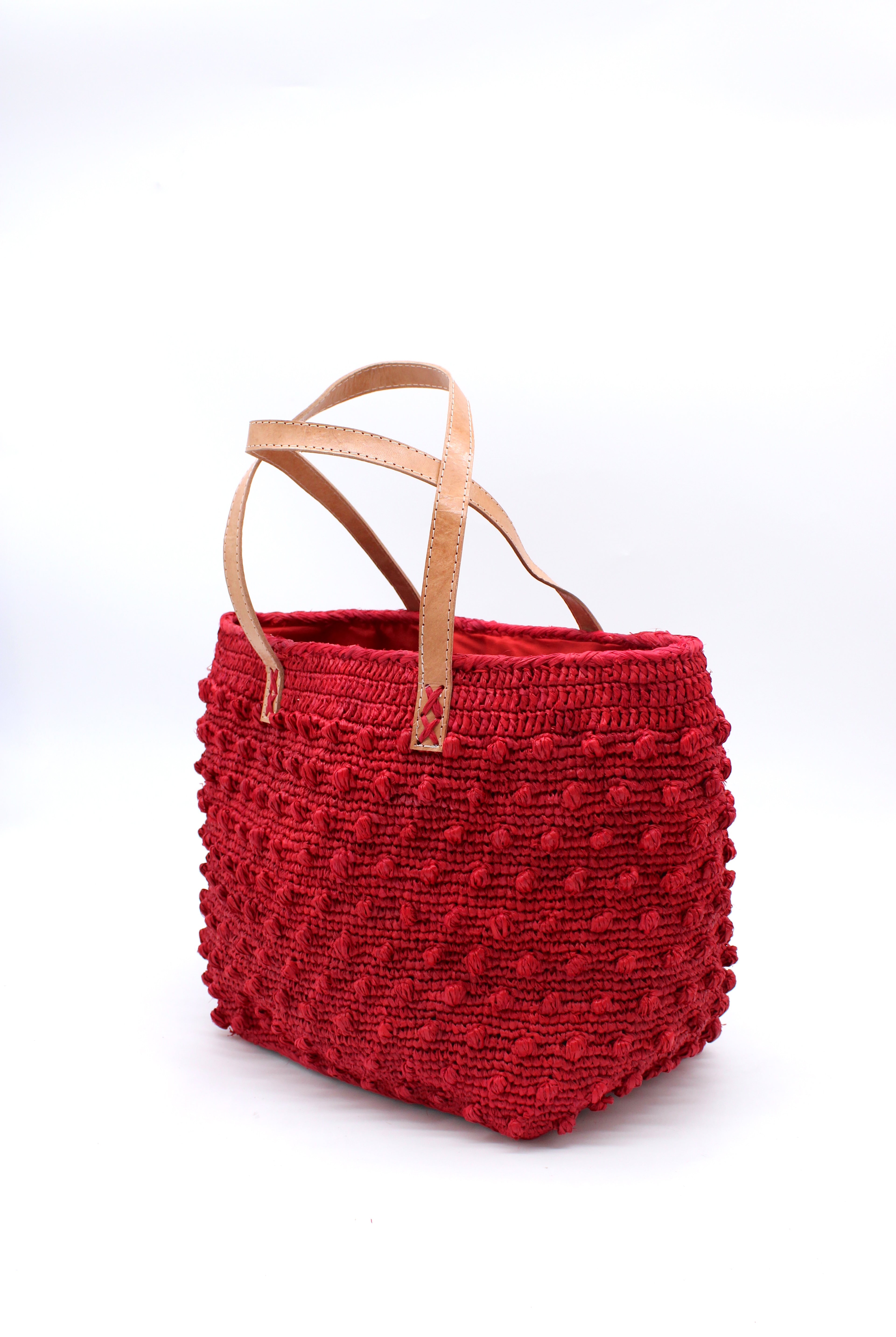 Side view Boucle Red Crochet Straw Basket Bag handmade woven raffia palm fiber in a solid hue of red in a supple nub/ball texture of horizontal bands around the bag with link weave around the top and loop crochet edging on the bottom and top plus leather handles beach bag shoulder bag purse - Shebobo