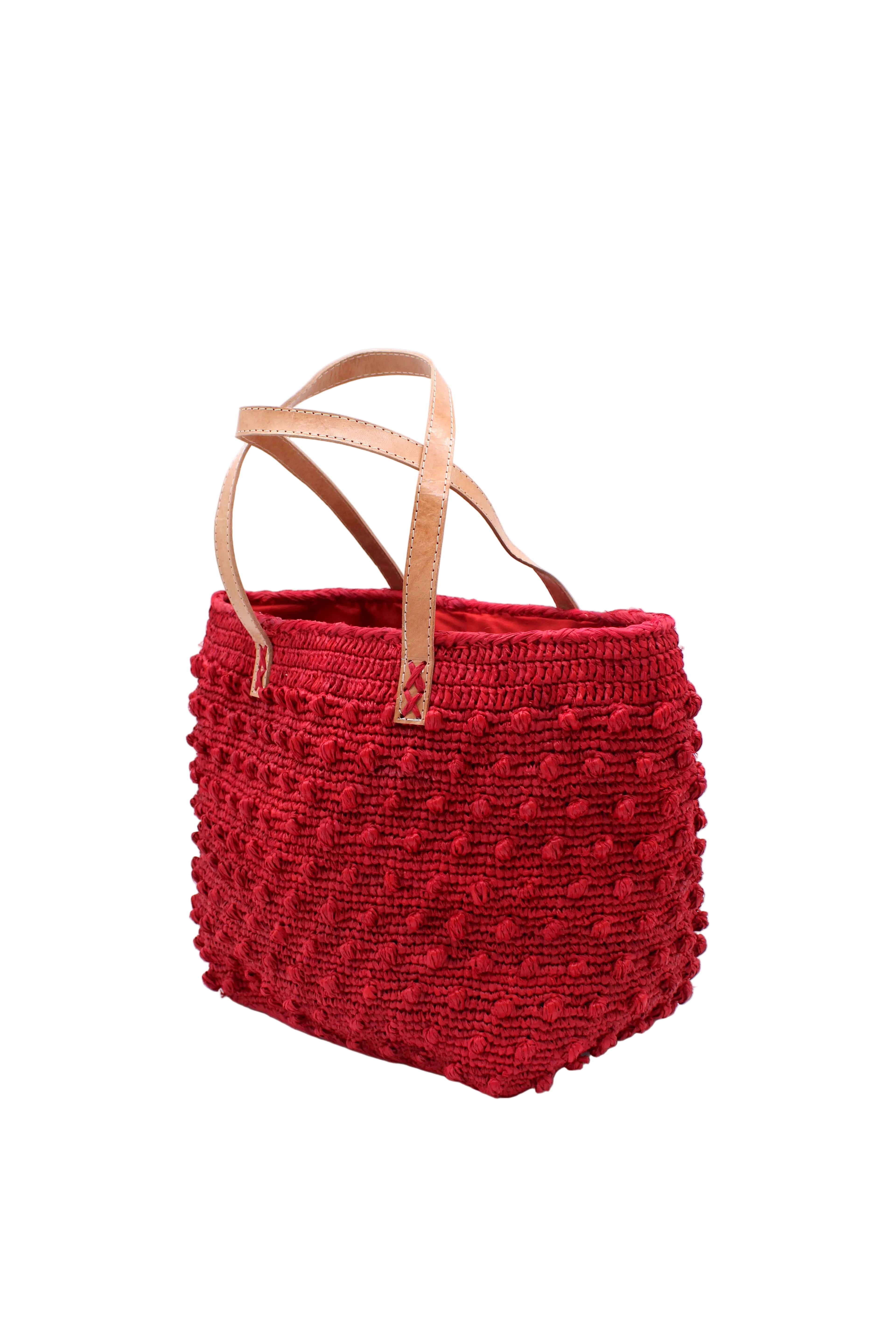 Side view Boucle Red Crochet Straw Basket Bag handmade woven raffia palm fiber in a solid hue of red in a supple nub/ball texture of horizontal bands around the bag with link weave around the top and loop crochet edging on the bottom and top plus leather handles beach bag shoulder bag purse - Shebobo