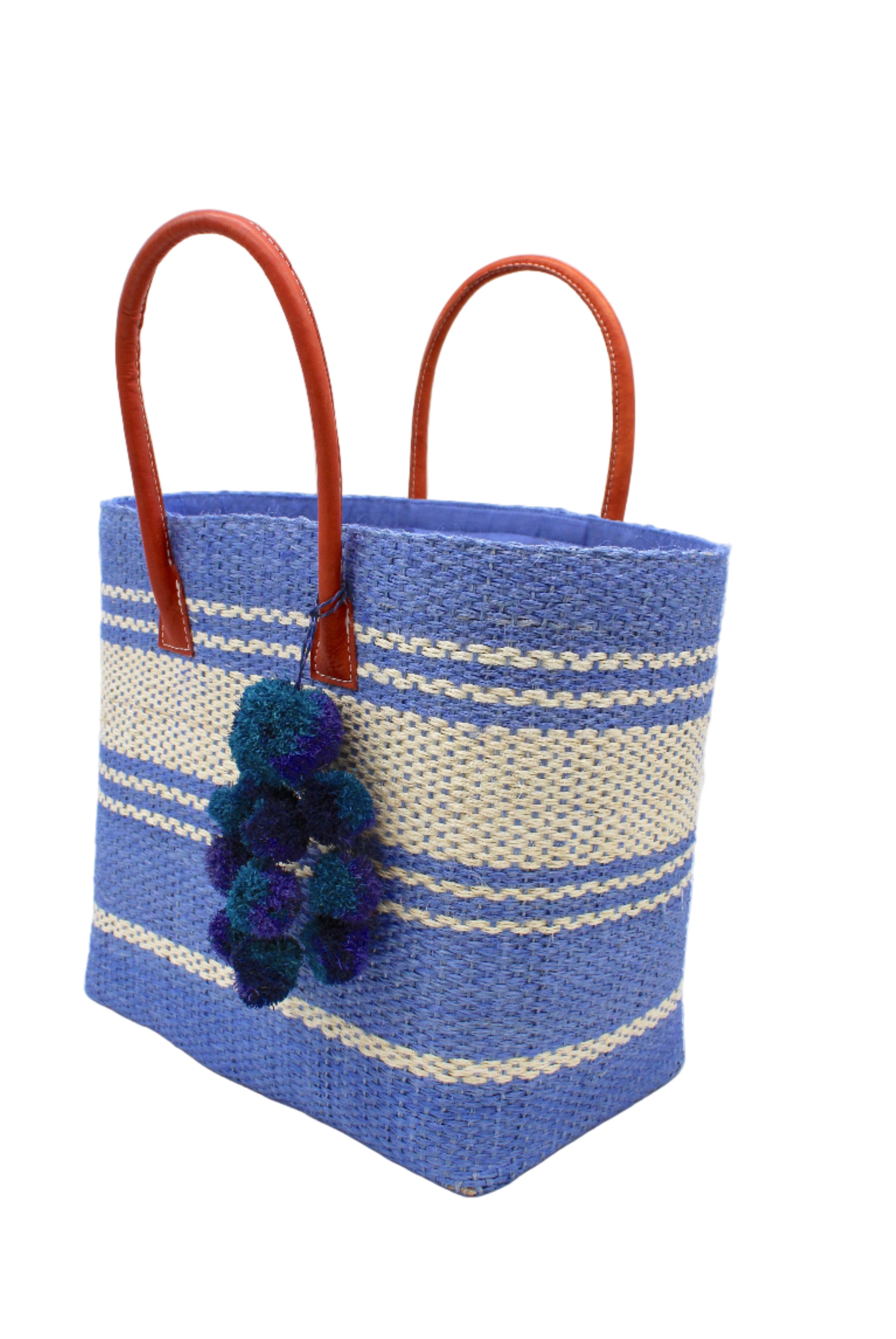 Side view Cabrillo Sisal Basket Bag with Waterfall Pompoms Charm Embellishment handmade natural sisal fiber woven into a multicolor two tone Denim retro/light/blue and natural straw color horizontal stripe pattern with muti-width bands of color plus leather handles and multicolor raffia charm shoulder bag beach bag - Shebobo