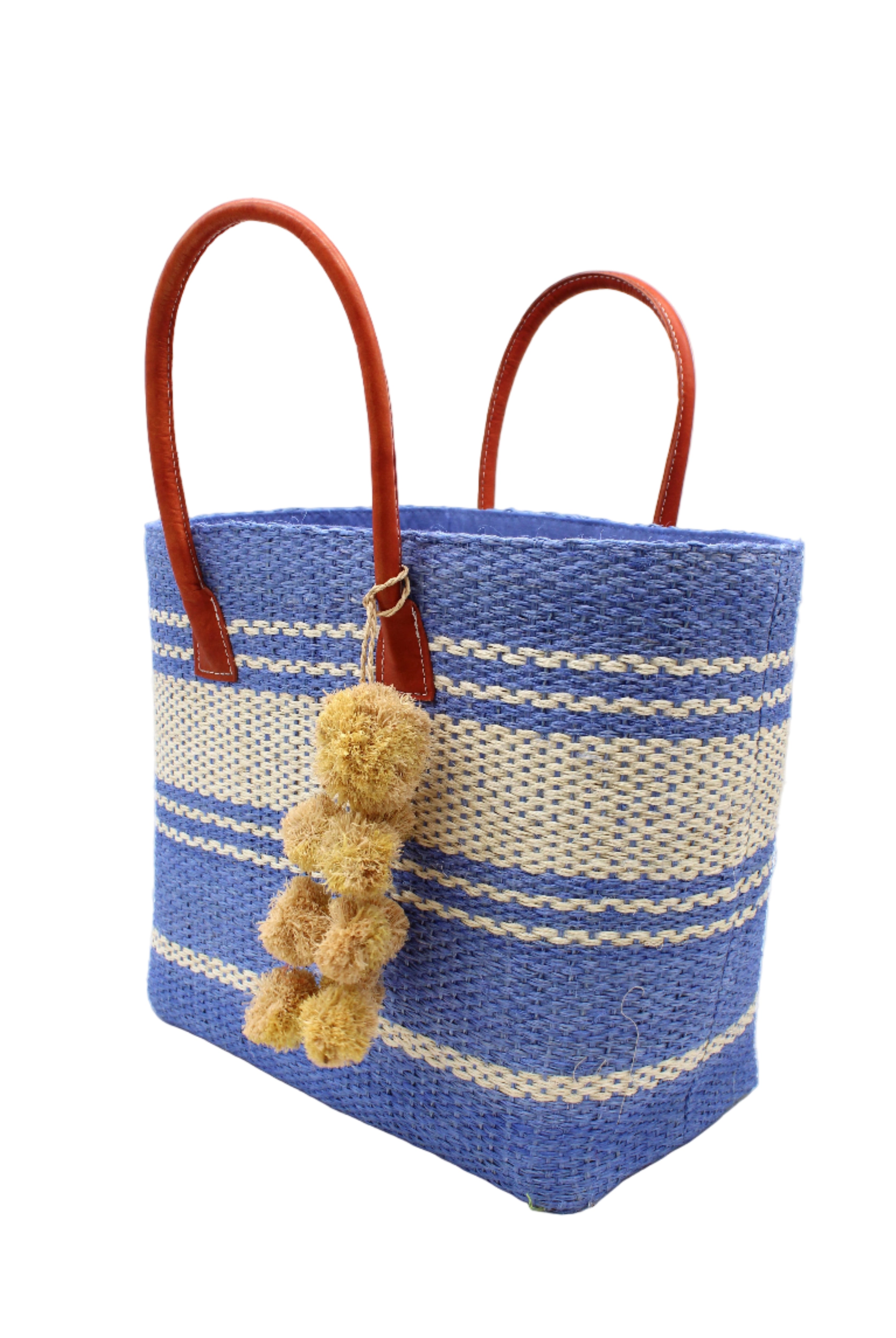 Side view Cabrillo Sisal Basket Bag with Waterfall Pompoms Charm Embellishment handmade natural sisal fiber woven into a multicolor two tone Denim retro/light/blue and natural straw color horizontal stripe pattern with muti-width bands of color plus leather handles and natural raffia charm shoulder bag beach bag - Shebobo