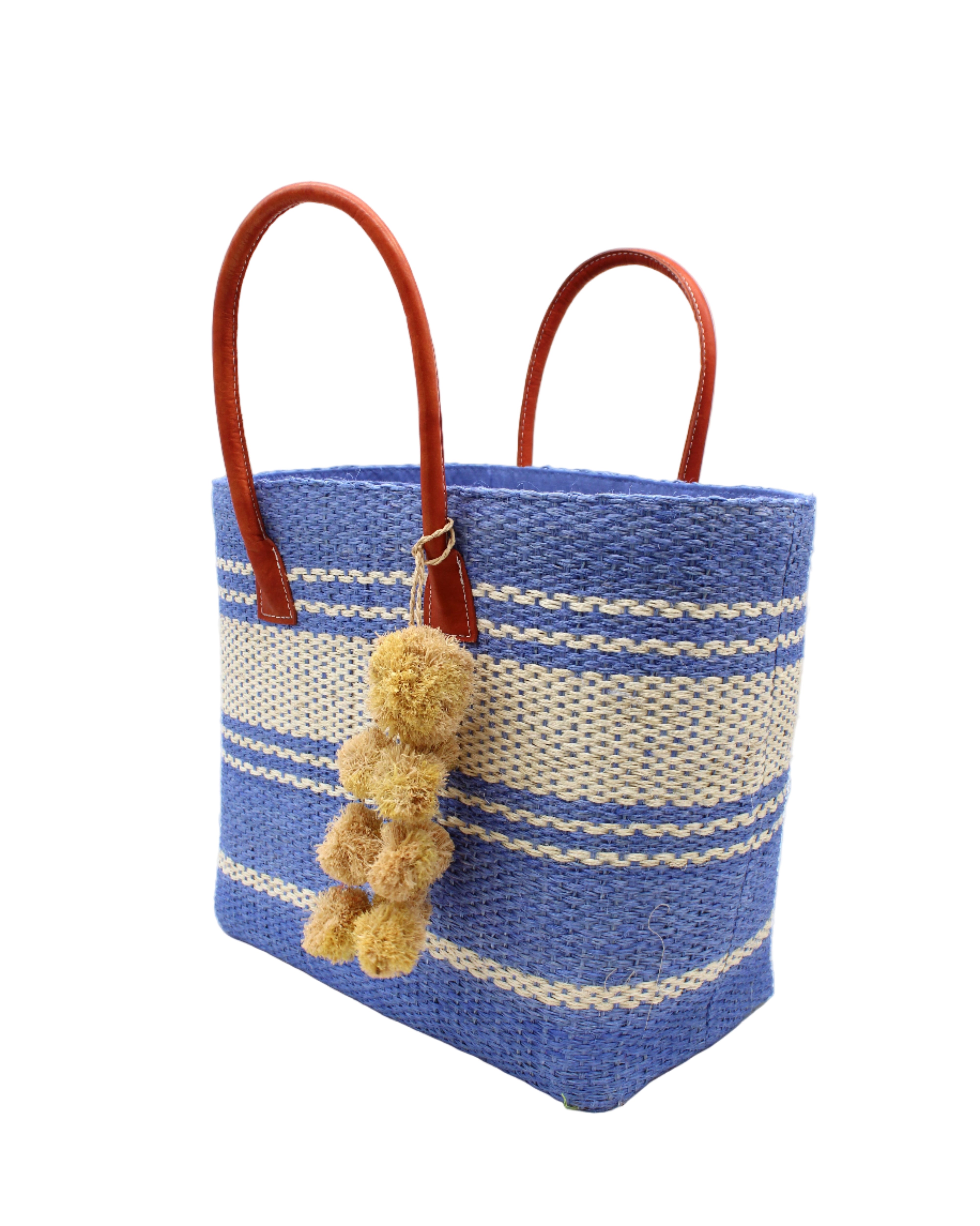 Side view Cabrillo Sisal Basket Bag with Waterfall Pompoms Charm Embellishment handmade natural sisal fiber woven into a multicolor two tone Denim retro/light/blue and natural straw color horizontal stripe pattern with muti-width bands of color plus leather handles and natural raffia charm shoulder bag beach bag - Shebobo