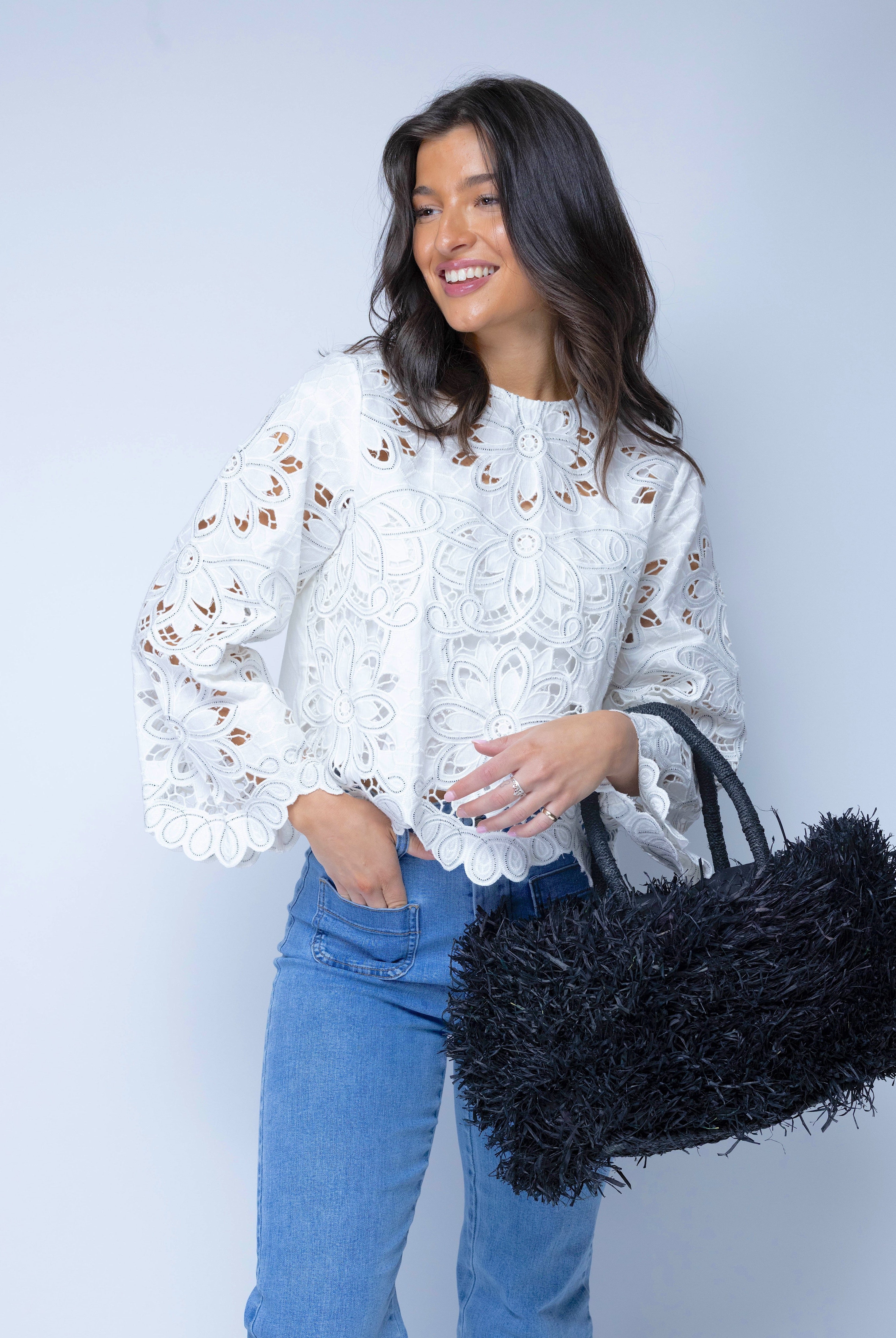 Model wearing Calypso Pompom Pouf Crochet Straw Basket Handbag handmade natural raffia palm fiber in a solid hue of Black with brushed fringe strands crochet and knotted into a pouf texture with matching wrapped handles purse - Shebobo