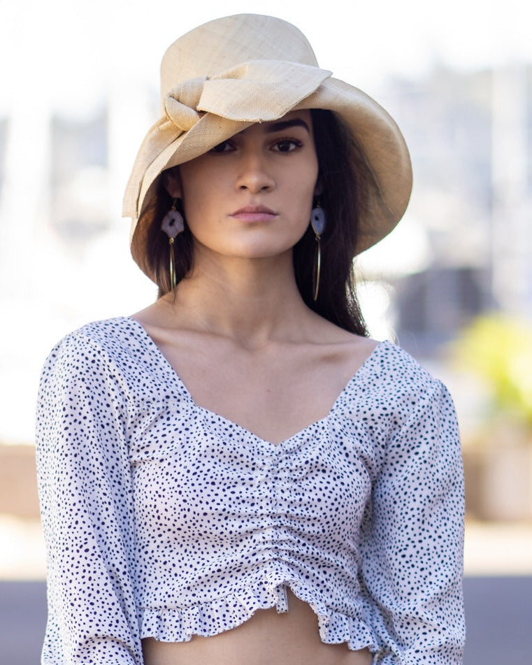 Model wearing Cara Natural straw color big bow embellishment handmade loomed raffia straw bucket style cloche sun hat - Shebobo