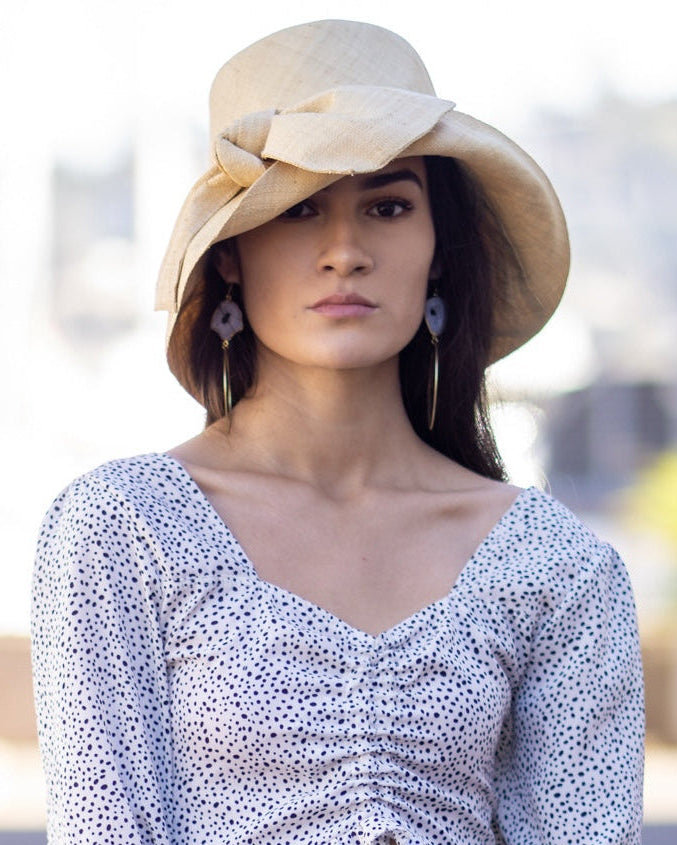 Model wearing Cara Natural straw color big bow embellishment handmade loomed raffia straw bucket style cloche sun hat - Shebobo