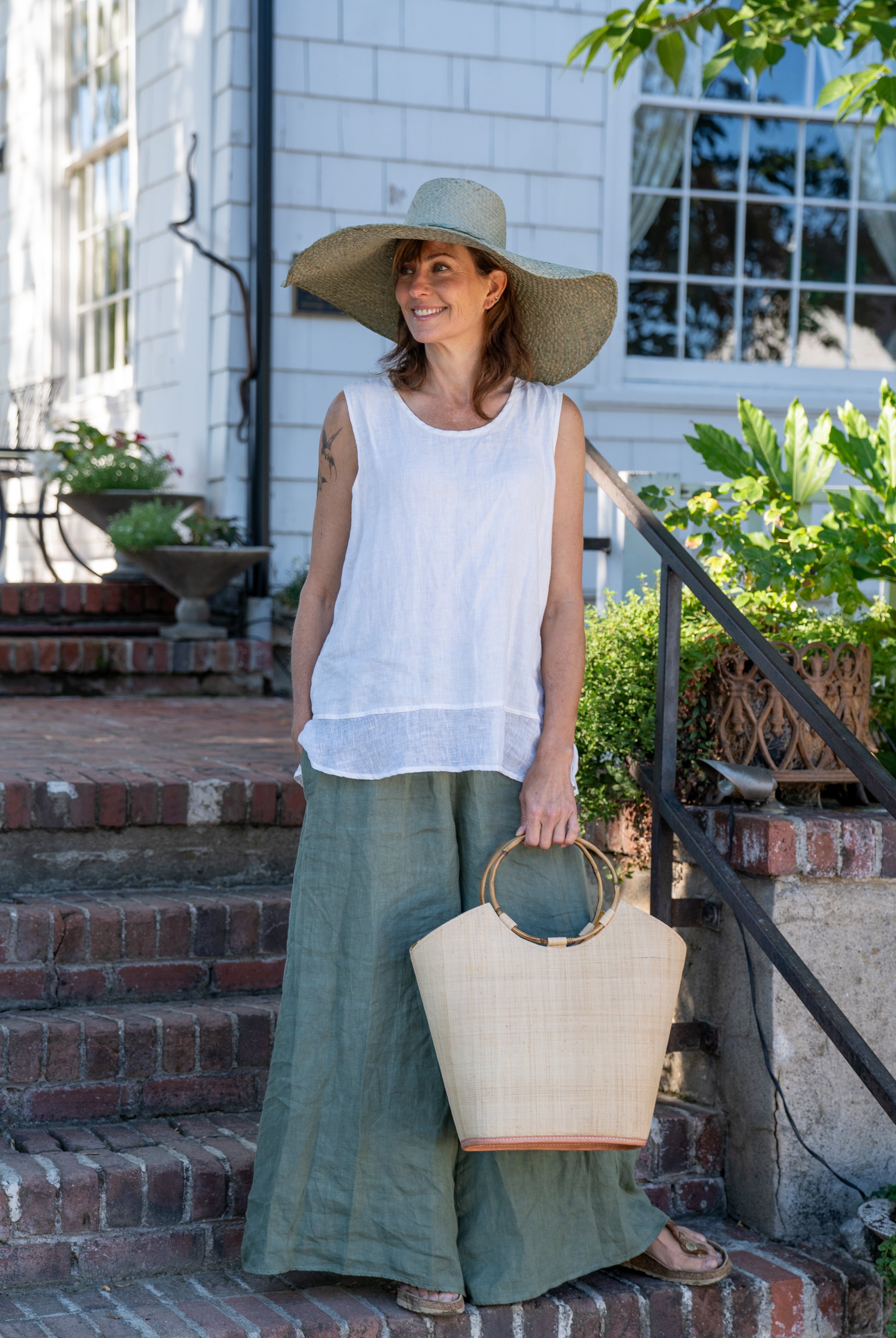 Model wearing Carmen Natural Straw Bucket Bag with Bamboo Handles handmade loomed raffia in a solid hue of natural straw color with assorted African print fabric liner handbag - Shebobo (with Natasha 7" Wide Brim Woven XL Straw Sun Hats)