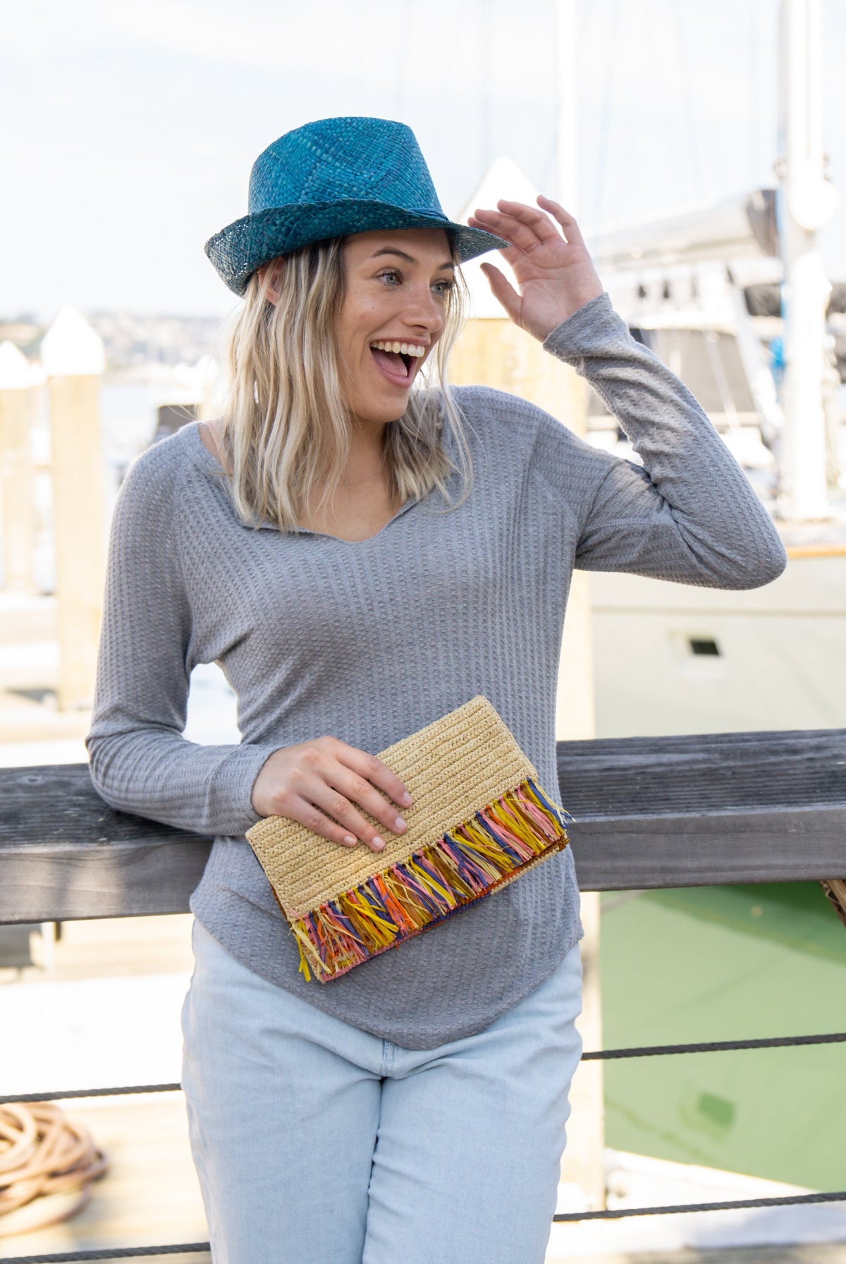 Model wearing Coco Fringe Crochet Straw Clutch Confetti Multicolor - orange yellow, pink, brown, and blue - and natural straw color two tone handmade purse with horizontal band of multicolor fringe - Shebobo