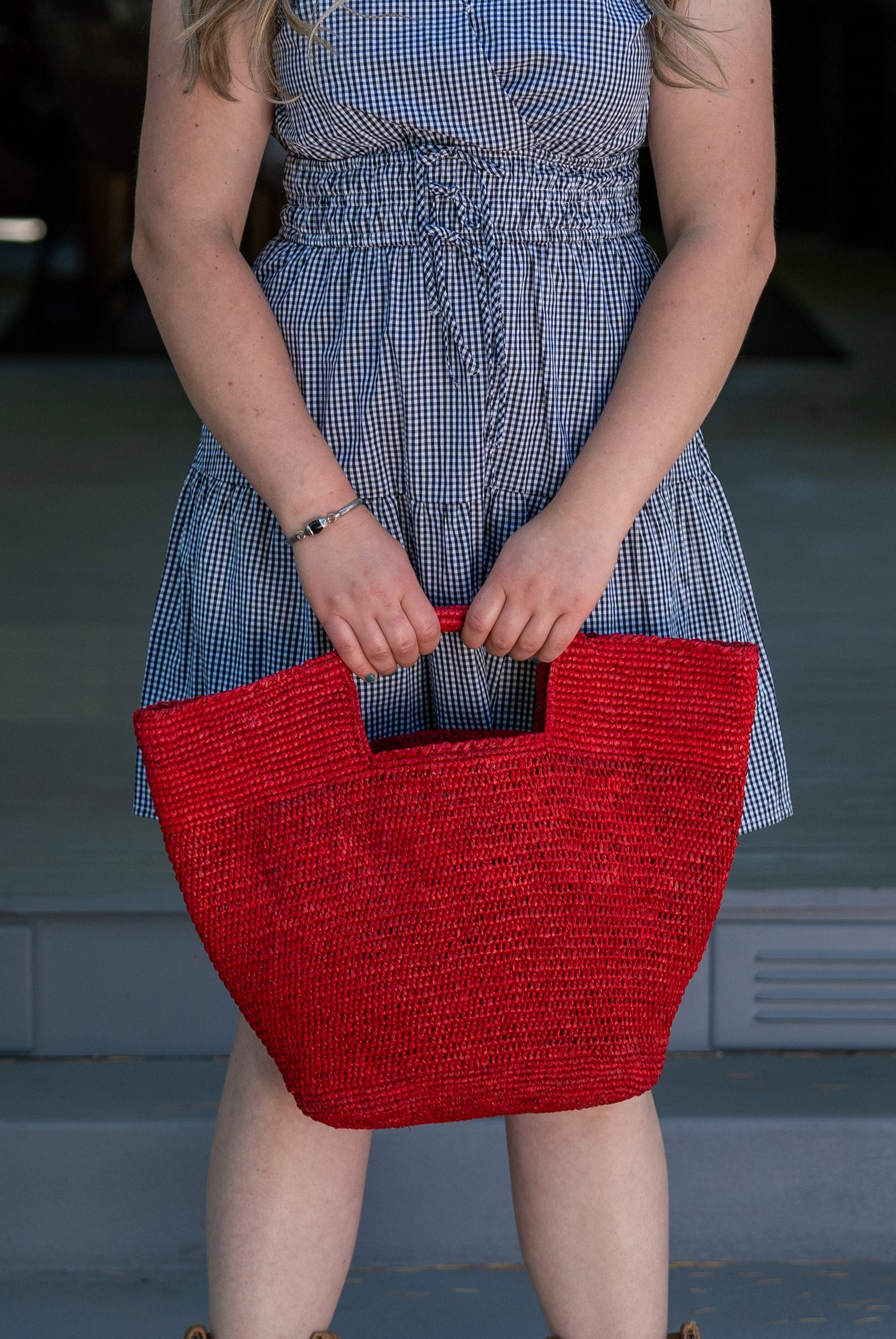 Model wearing ConCon Crochet Straw Basket handmade woven raffia palm fiber in a solid hue of red making a textured link pattern handbag tote - Shebobo