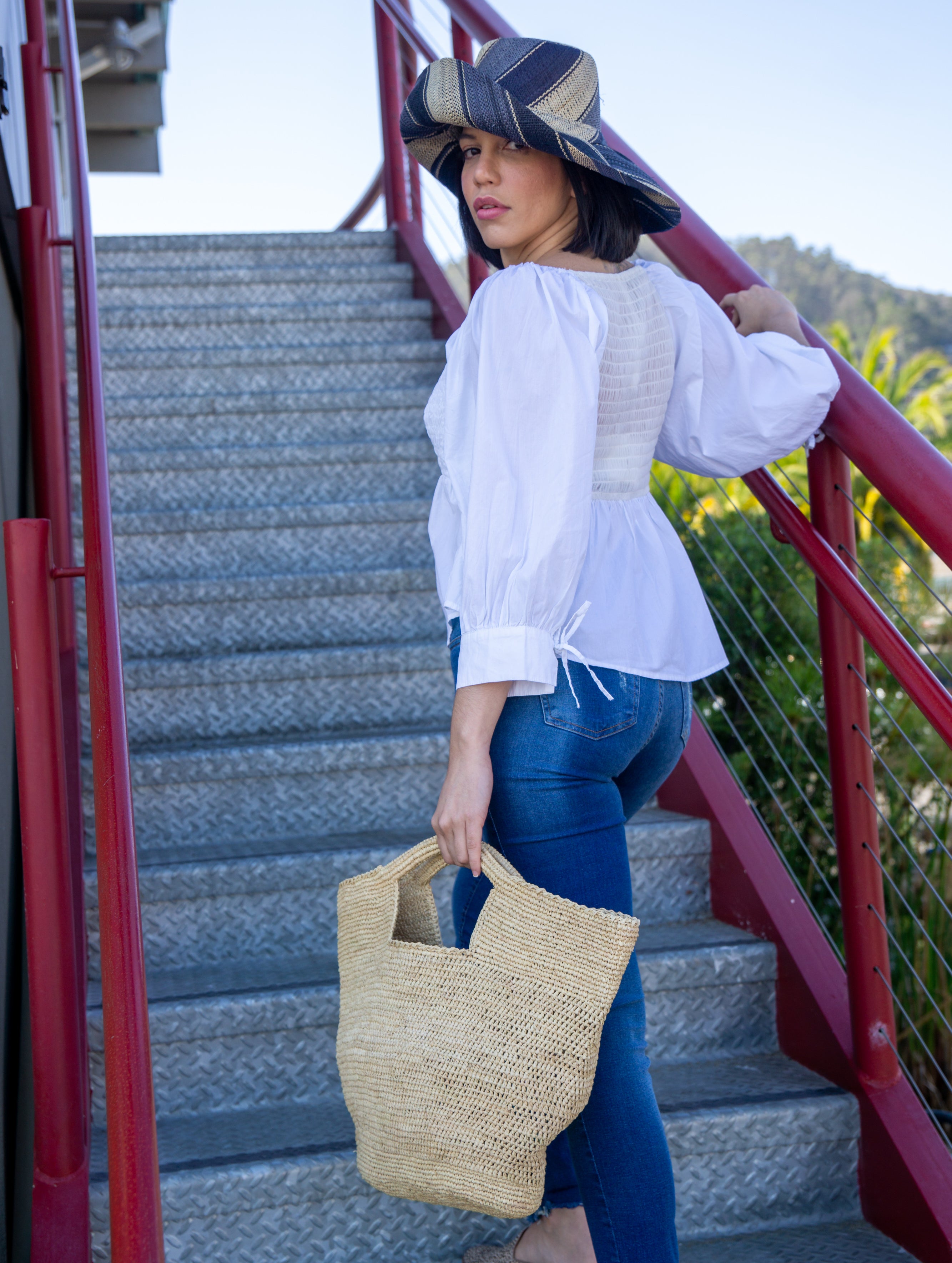 Model wearing ConCon crochet straw basket natural raffia straw color handbag textural bag - Shebobo (with 5" Brim Black Swirl Packable Straw Sun Hat)