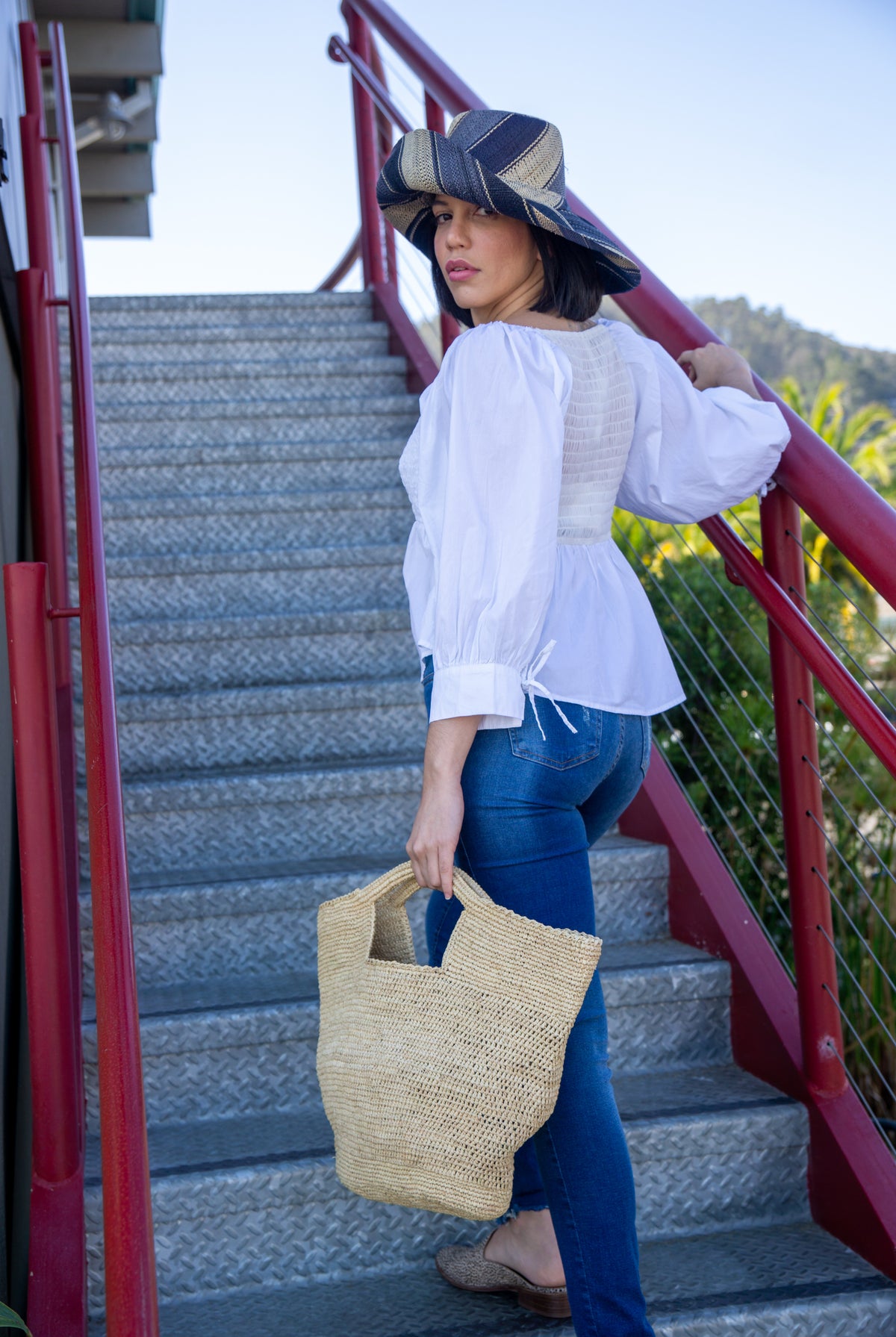 Model wearing ConCon crochet straw basket natural raffia straw color handbag textural bag - Shebobo (with 5" Brim Black Swirl Packable Straw Sun Hat)