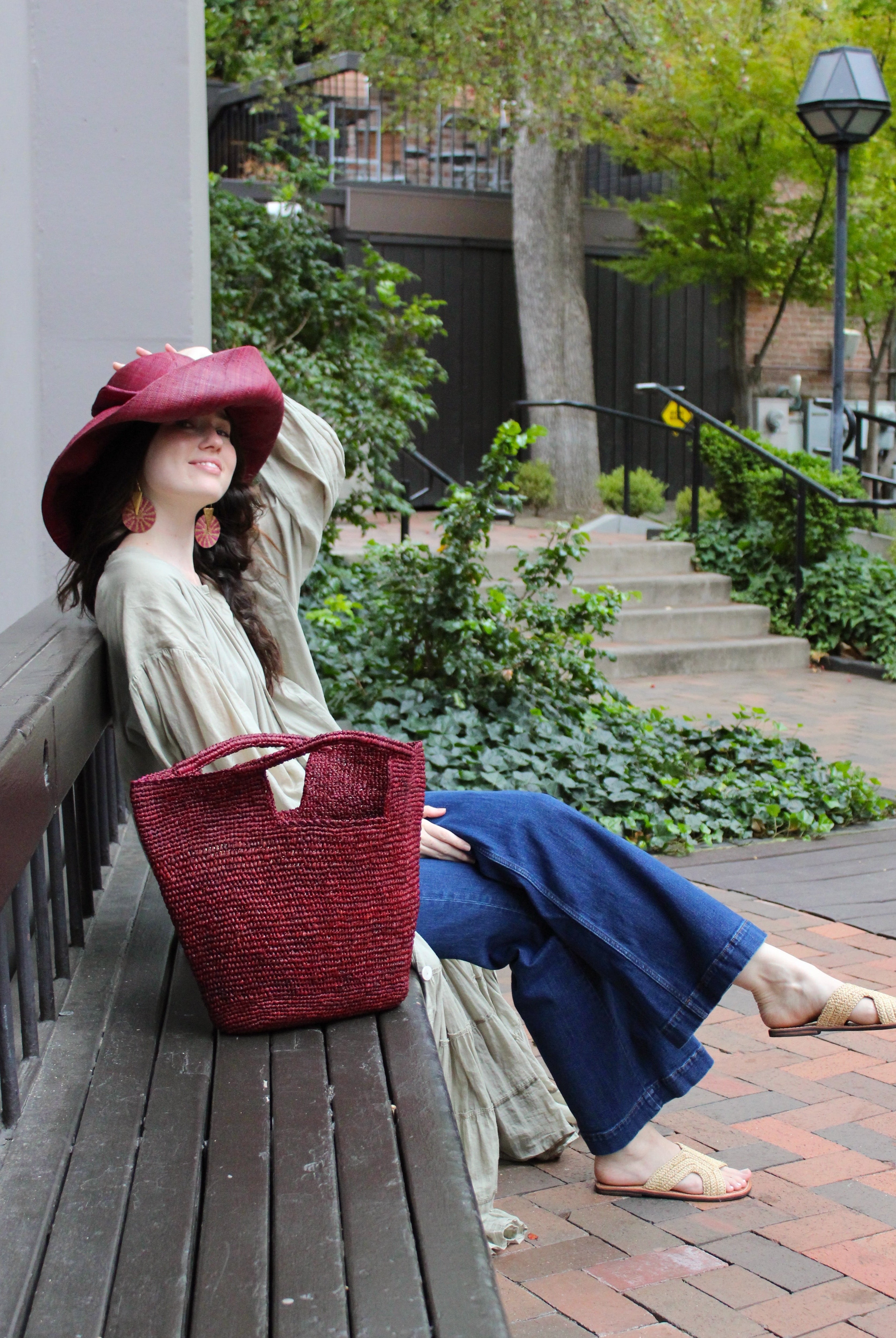 Model wearing ConCon Crochet Straw Basket handmade woven raffia palm fiber in a solid hue of umberwine bordeaux/claret/deep/dark/purple/red making a textured link pattern handbag tote - Shebobo (with Audrey 5" & 7" Wide Brim Big Bow Solid Color Packable Straw Sun Hats and Lizzie Crochet Straw & Leather Sandal Shoes)